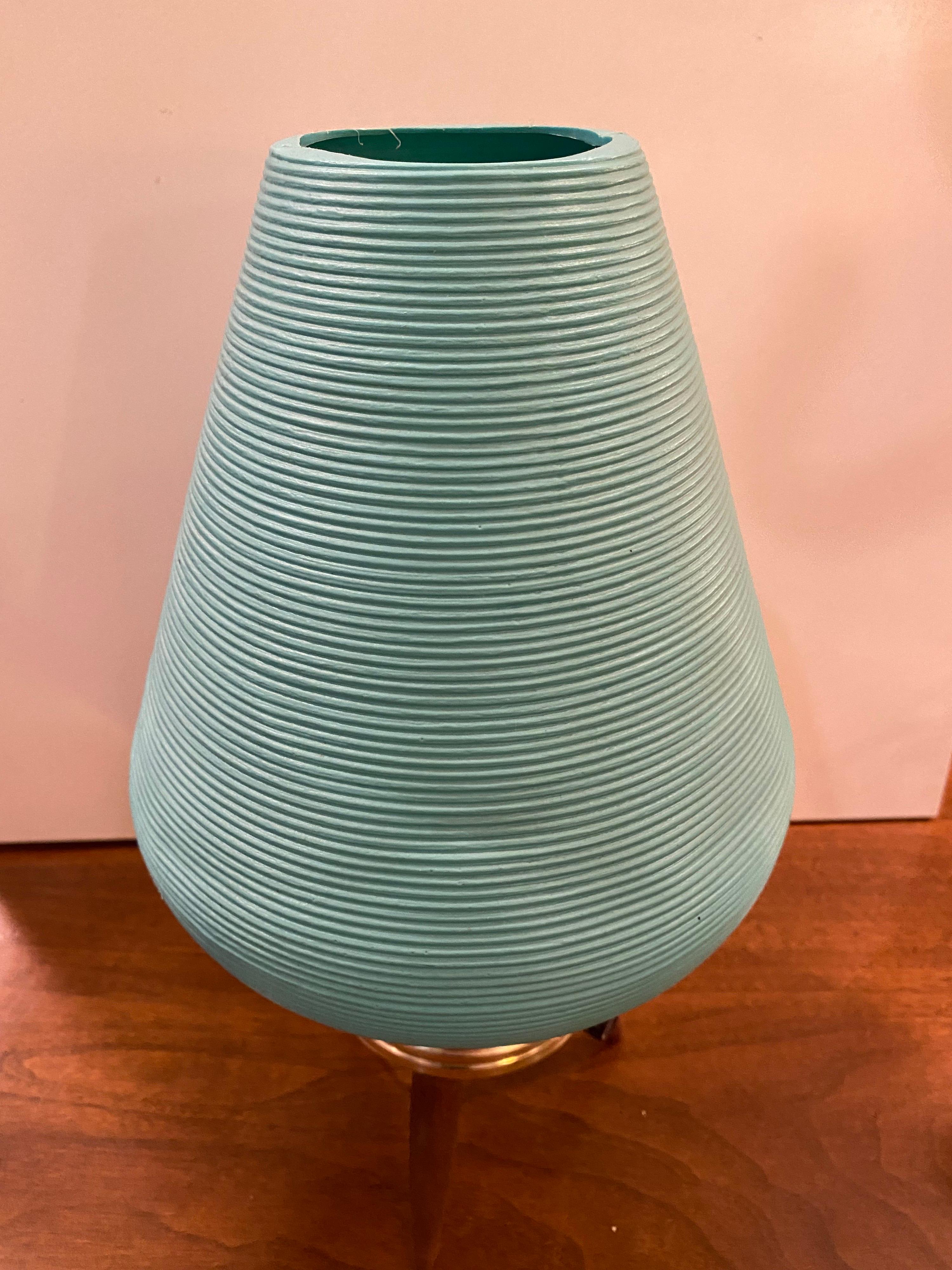 Small plastic beehive table lamp with a metal body and 3 wood legs forming a tripod base. Turn switch coming out of metal frame adds ease to turning this aqua-blue lamp on!