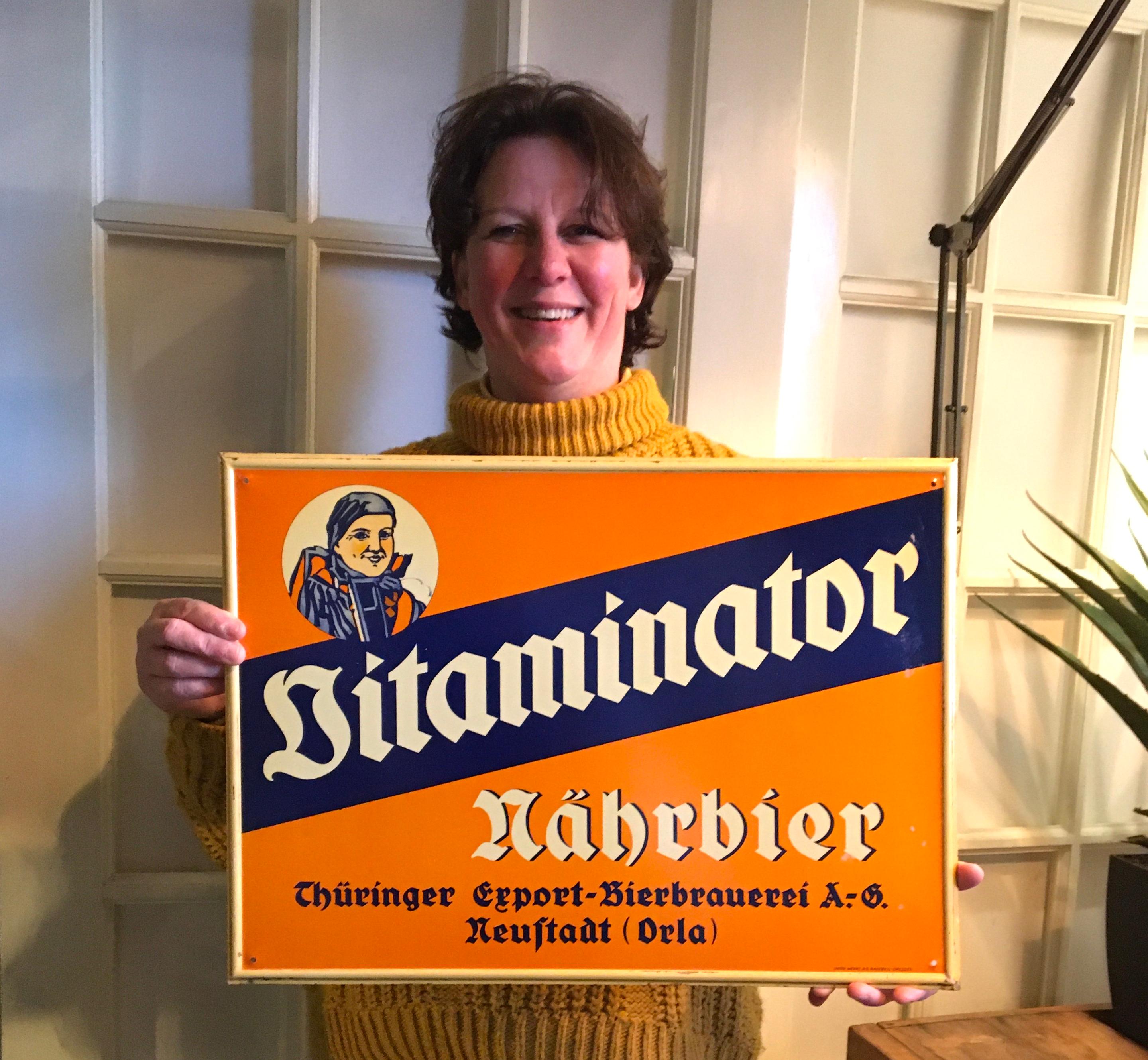 Tin advertising sign for German Beer .
This Thuringia beer sign for Vitaminator Nährbier
was made by Union - Werke A-G Radebeul Dresden Germany in the 1940s.
It is an orange with blue sign with nice lettering. 
In beautiful condition with some