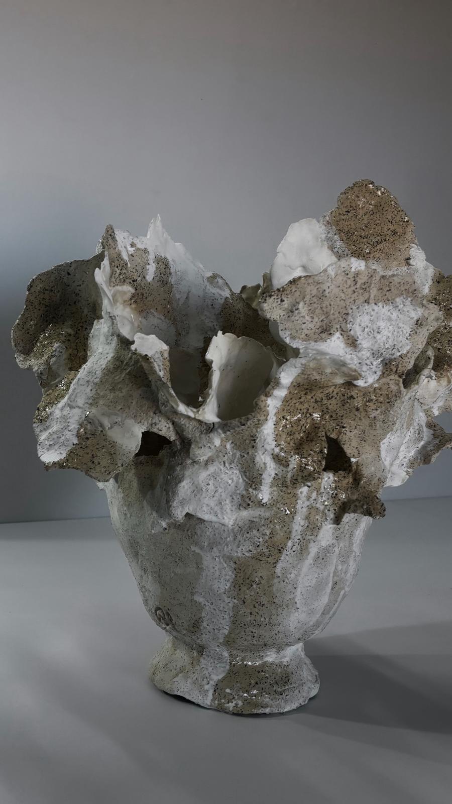 Ce vase, dans les tons crème et brun moucheté de terre, s'élève dans un mouvement presque sauvage, comme un sol dont les bords ont été soulevés par le vent, ou comme une mer prise dans un seul instant de grondement. Ses lignes sont irrégulières, ses