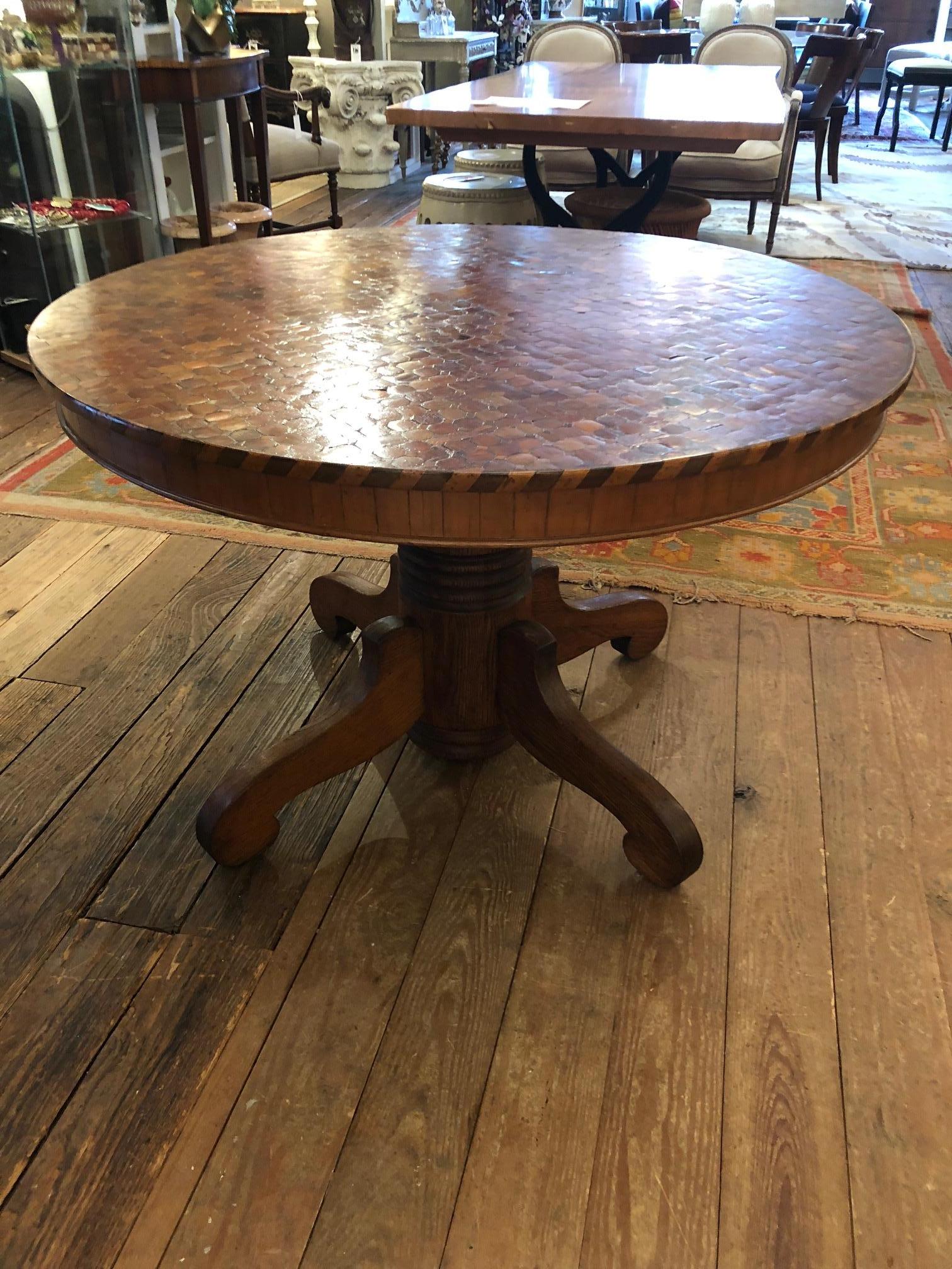 A rare find of a small round dining table or stunning center table having a one of a kind antique top, circa 1860, of inlaid round wood chips that beguiles the eye with its variety of rich hues and pattern. There is stunning parquet inlay around the