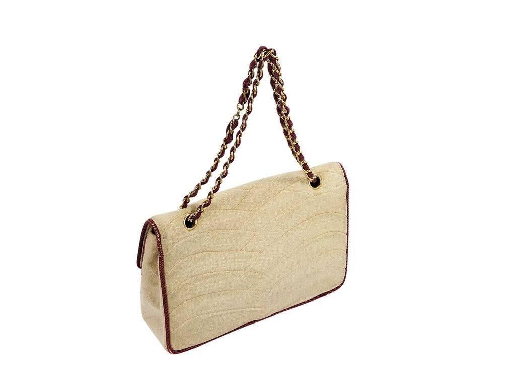 Product details:  Vintage beige quilted jersey shoulder bag by Chanel.  Burgundy trimming.  Dual chain shoulder straps.  Front flap with push-lock closure.  Lined interior with inner zip and slide pockets.  Goldtone hardware.  10.5