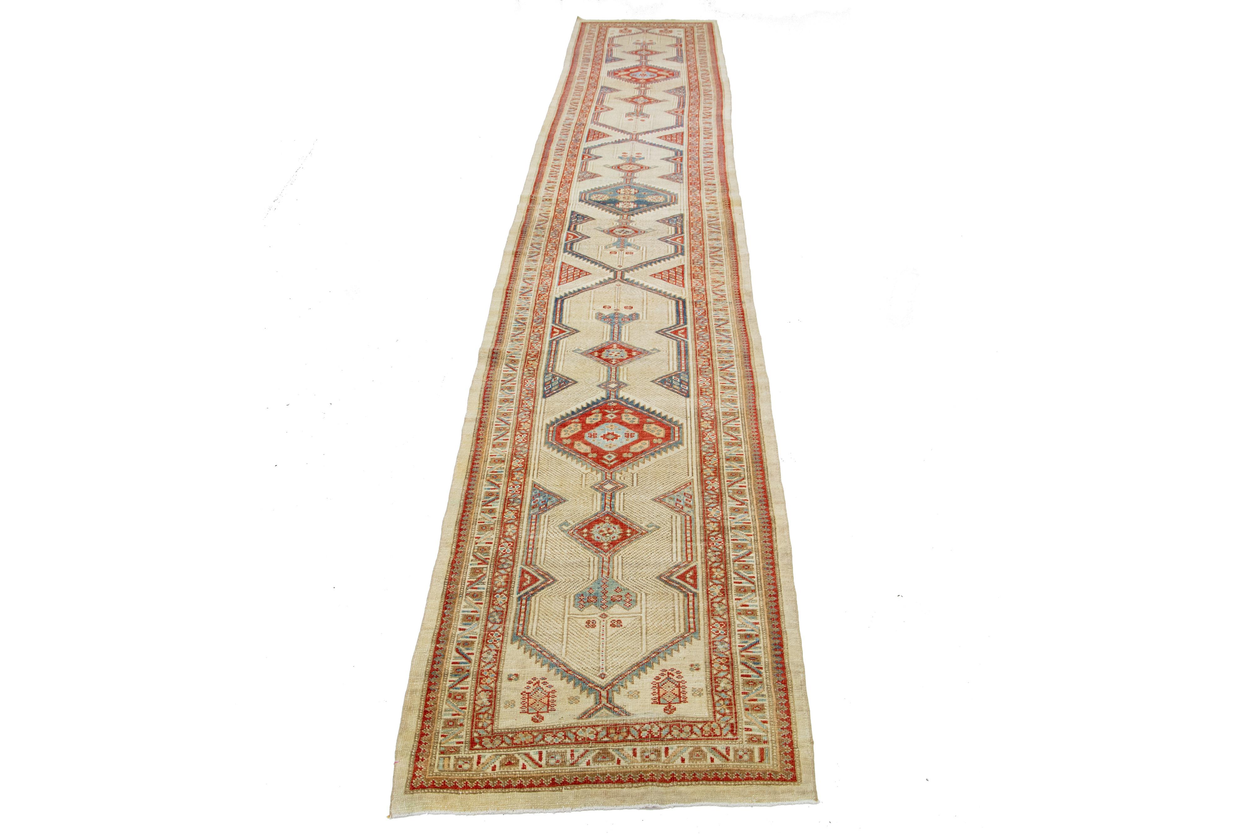 Antique Persian Serab hand-knotted wool runner with beige-cream color field. This piece has rust and blue accents in an all-over tribal design. 

This rug measures 3' x 18'4