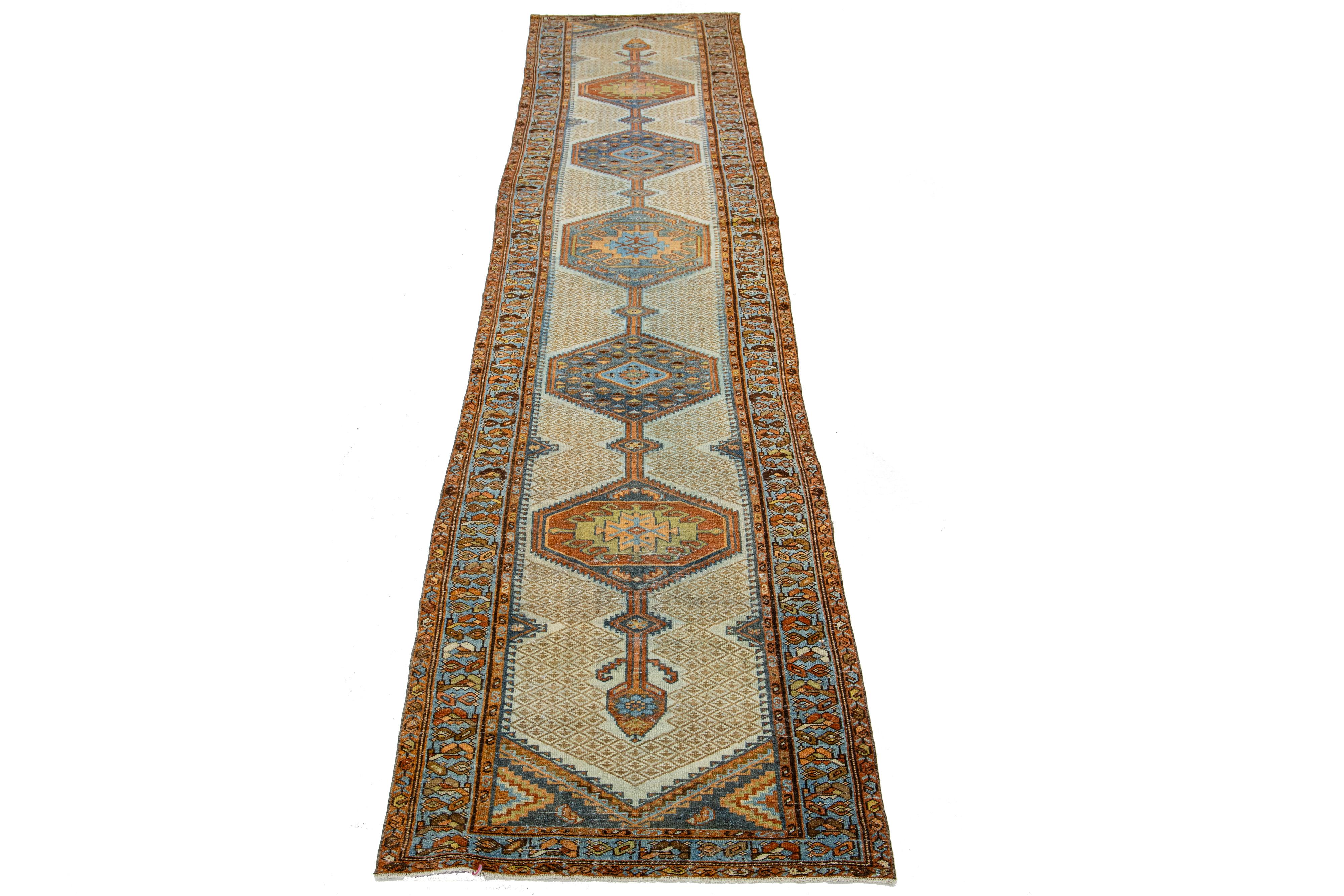 Beautiful antique Persian hand-knotted wool runner with a beige color field. This piece has rust and blue accents in a gorgeous multi-medallion design.

This rug measures 3'3