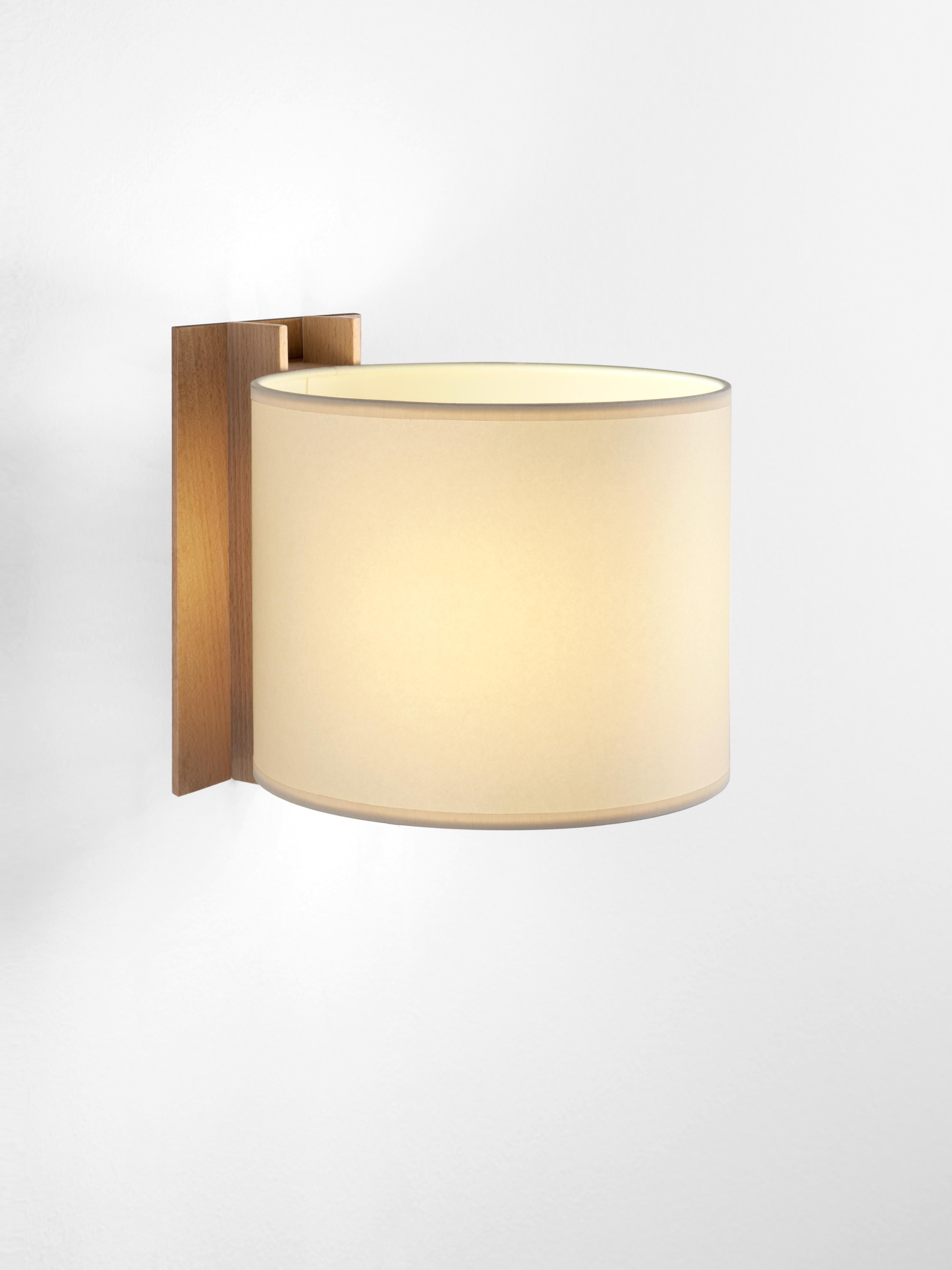 Beige and Beech TMM Corto wall lamp by Miguel Milá
Dimensions: D 20 x W 23 x H 20 cm
Materials: Metal, beech wood, parchment lampshade.
Direct wall.
Available in beech or walnut and in white or beige lampshade.
Available with plug or direct