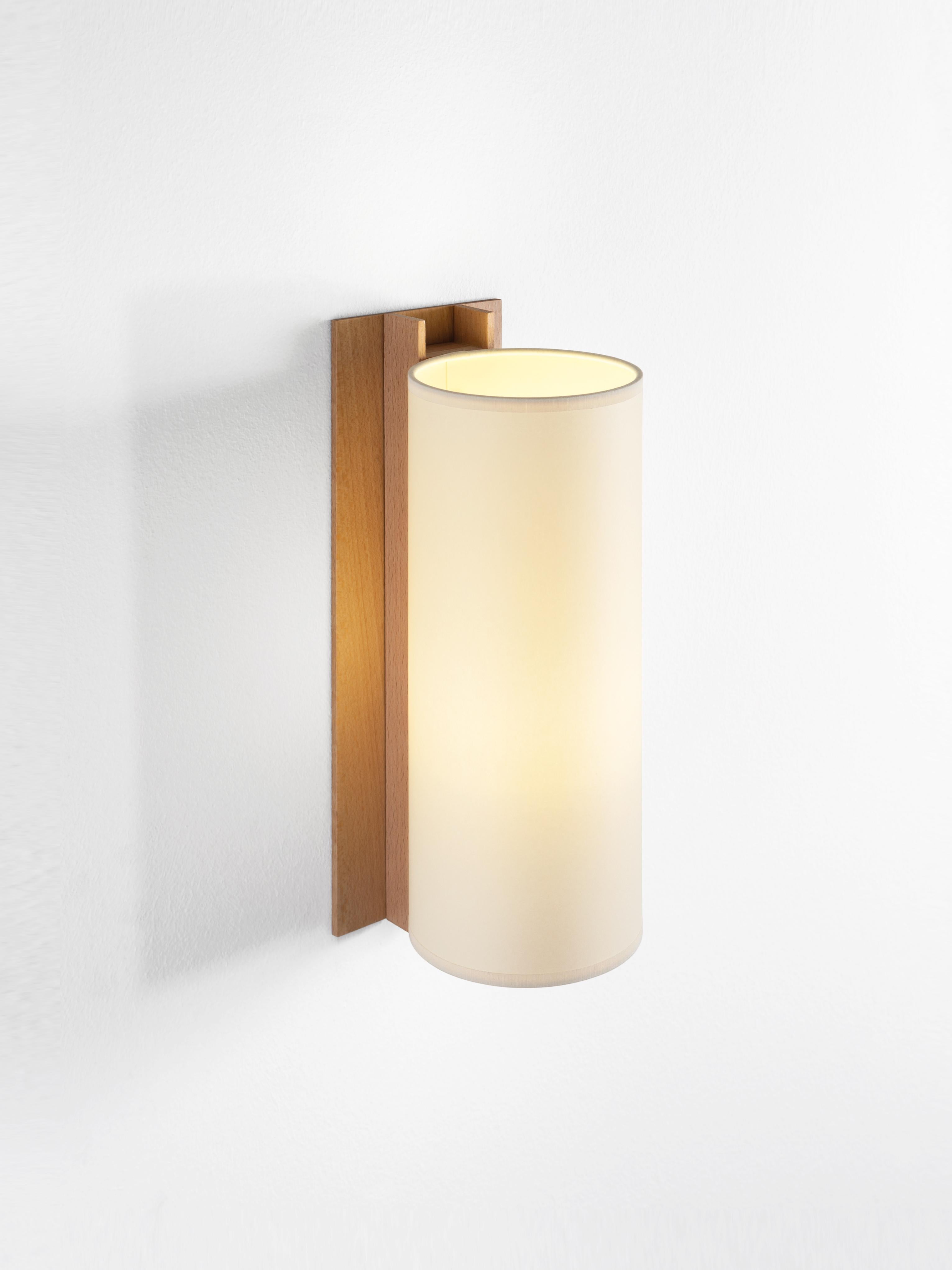 Beige and beech TMM largo wall lamp by Miguel Milá
Dimensions: D 12 x W 15 x H 34 cm
Materials: Metal, beech wood, parchment lampshade.
Available in beech or walnut and in white or beige lampshade.

The long and short wall lamps belonging to