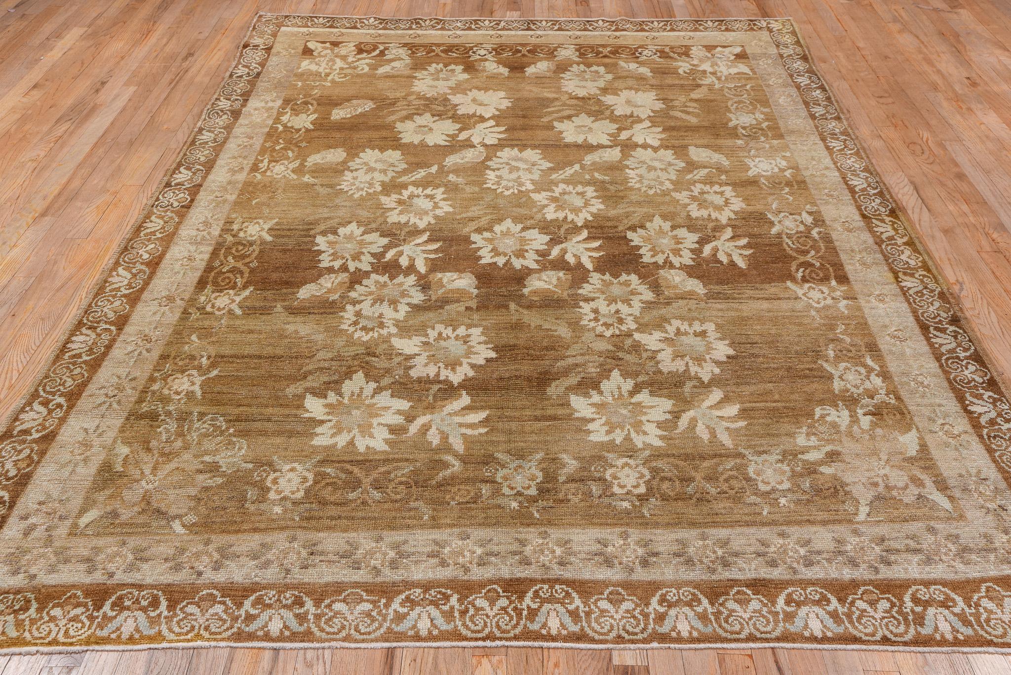 This rug presents a tranquil and sophisticated palette of earthy browns and soft beige, exuding a sense of quiet elegance. The field is adorned with large, blooming floral motifs, meticulously arranged to create a harmonious flow across the rug's
