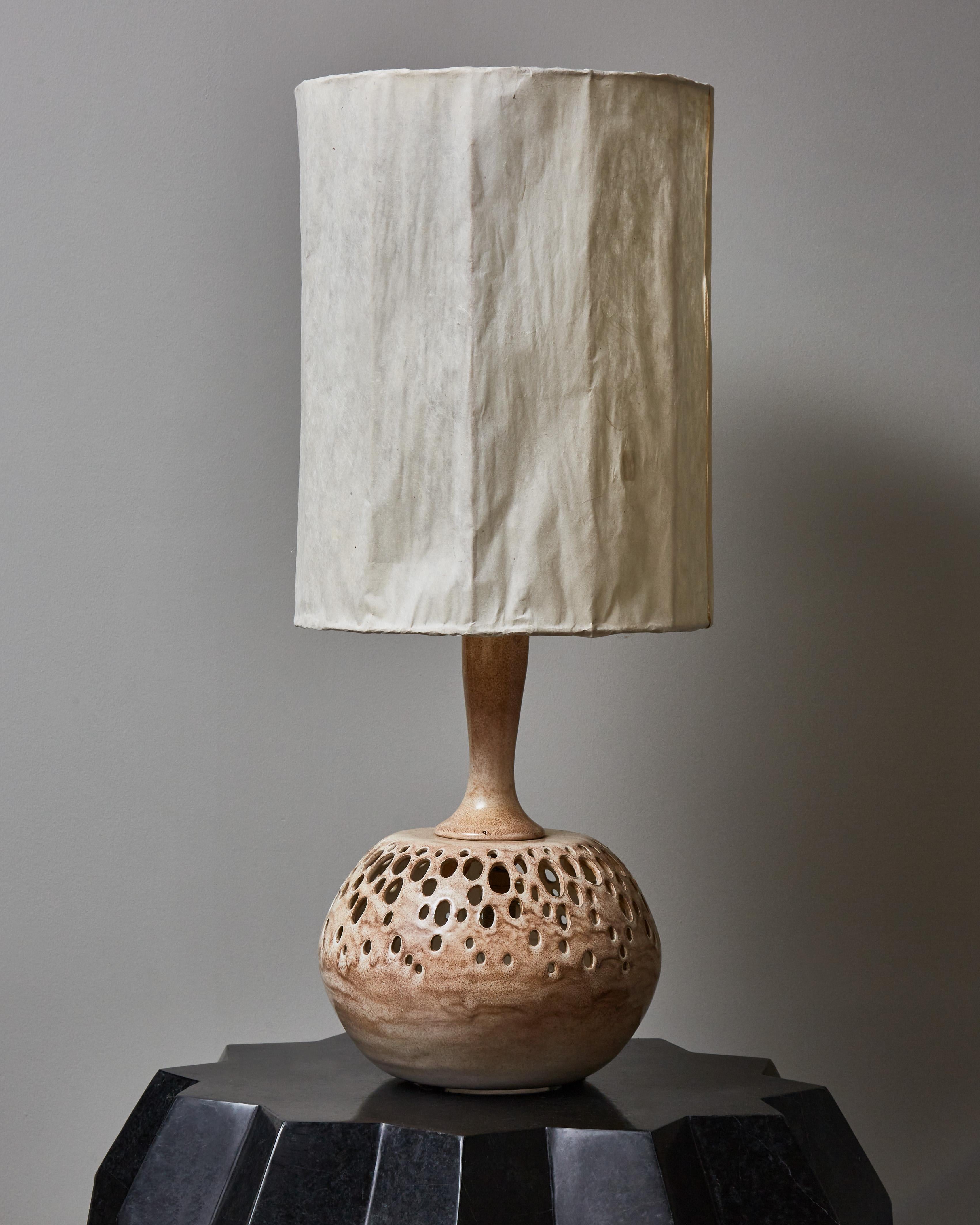 Glazed ceramic table lamp in beautiful tones of light beige and brown with openwork motifs from where light is defused. It comes with its original rice paper shade and is signed with an unidentified monotype “IS” on the bottom of the base.