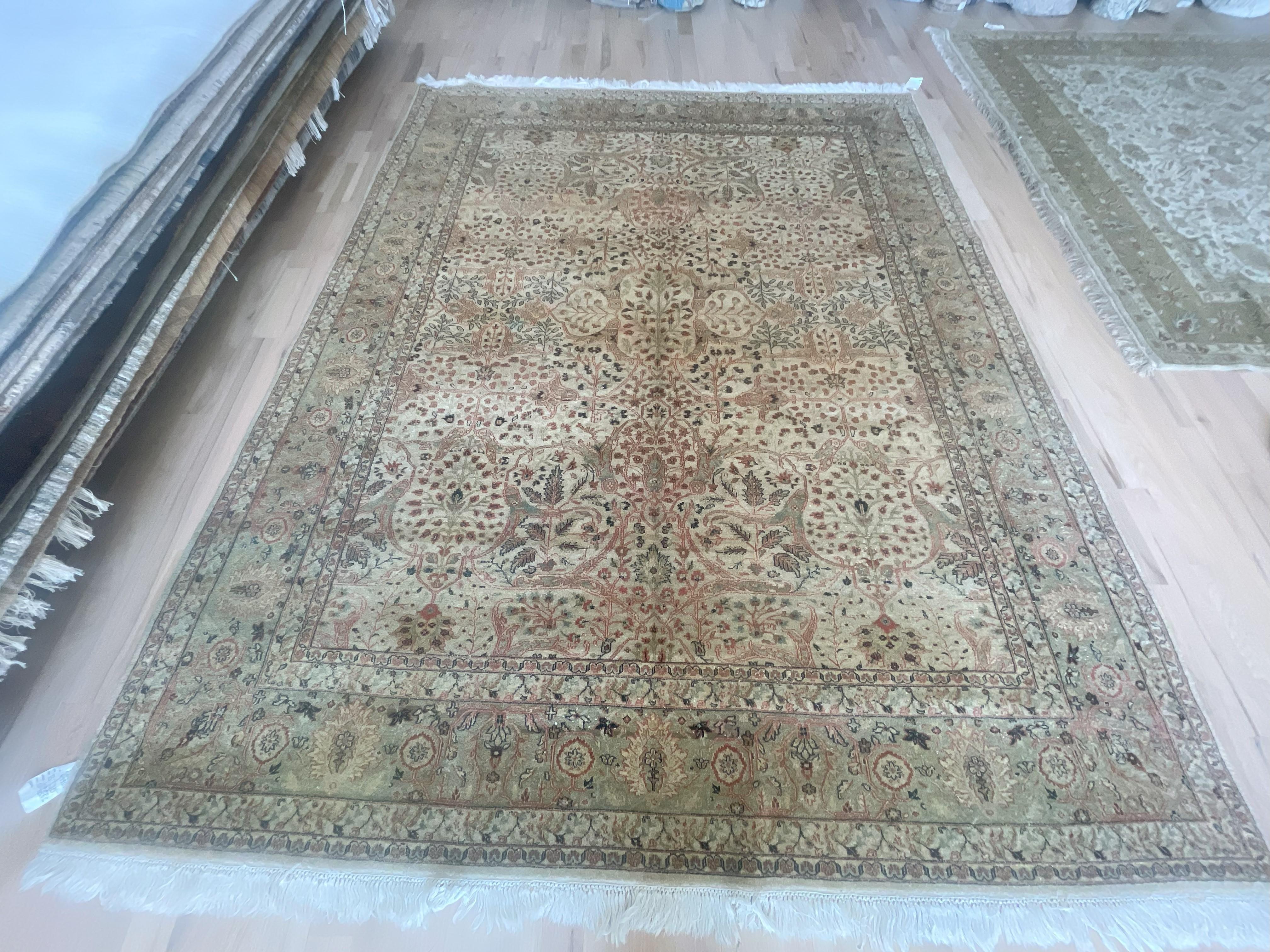 Un encantador motivo floral sobre un panel central beige y un amplio borde verde lo convierten en una excelente pieza de acompañamiento para la madera y los tonos naturales en el comedor o el salón. La duradera lana anudada a mano puede soportar