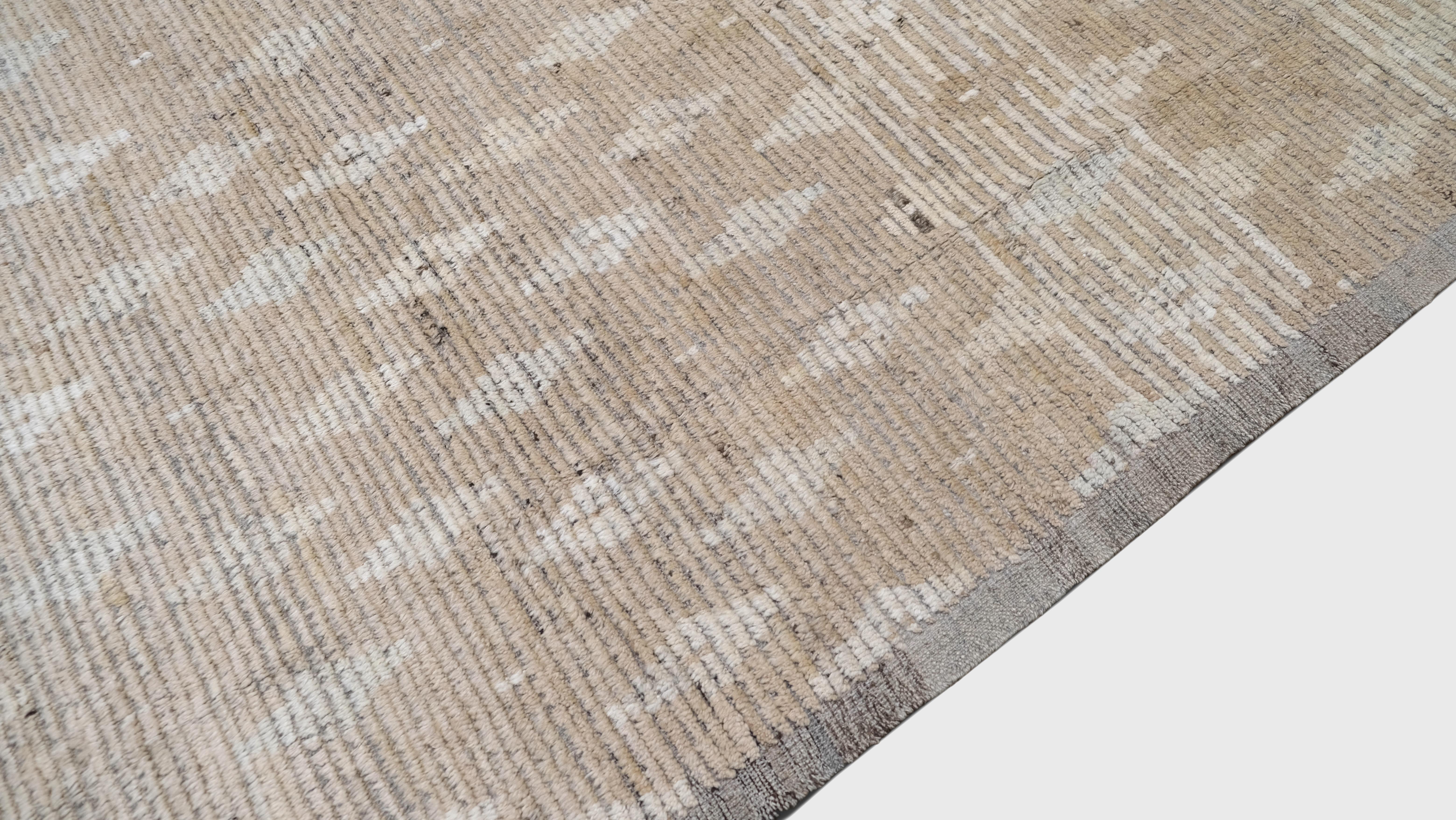 Discover the timeless beauty of this hand-knotted wool rug, featuring an intricate geometric pattern in warm beige and soft ivory hues. The repeating diamond motifs, inspired by traditional tribal designs, create a balanced and elegant aesthetic