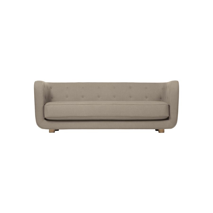 Beige and smoked oak Raf Simons Vidar 3 Vilhelm sofa by Lassen.
Dimensions: W 217 x D 88 x H 80 cm. 
Materials: Textile, oak.

Vilhelm is a beautiful padded three-seater sofa designed by Flemming Lassen in 1935. A sofa must be able to function