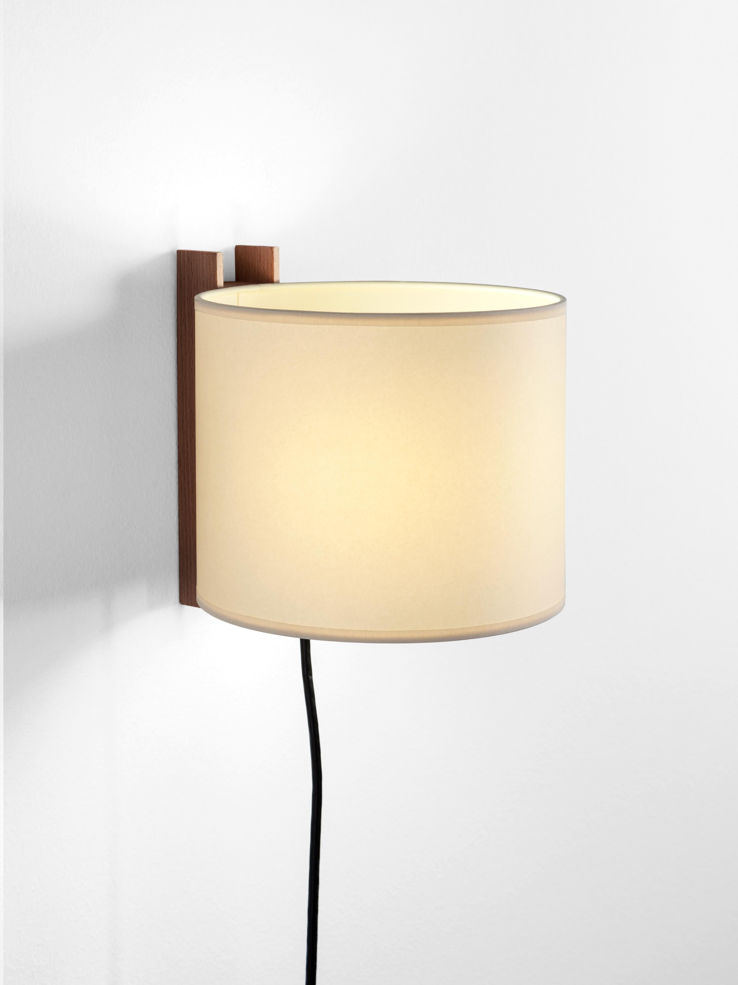 Beige and walnut TMM Corto wall lamp by Miguel Milá
Dimensions: D 20 x W 23 x H 20 cm
Materials: Metal, walnut wood, parchment lampshade.
With plug.
Available in beech or walnut and in white or beige lampshade.
Available with plug or direct