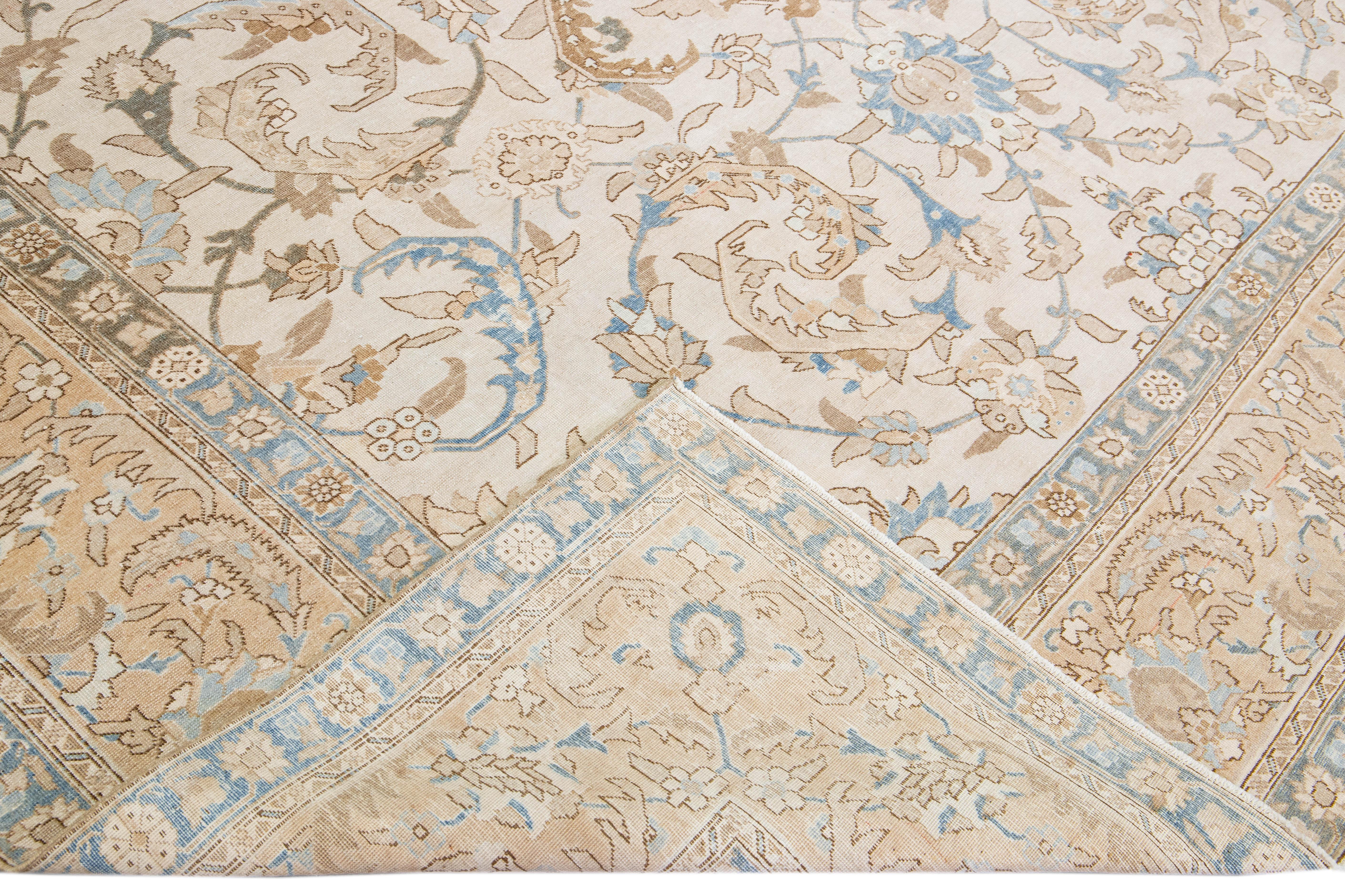 Beautiful antique Persian Tabriz hand-knotted wool rug with a beige field. This piece has a rusted floral frame and blue accents in an all-over gorgeous floral design.

This rug measures: 9'9