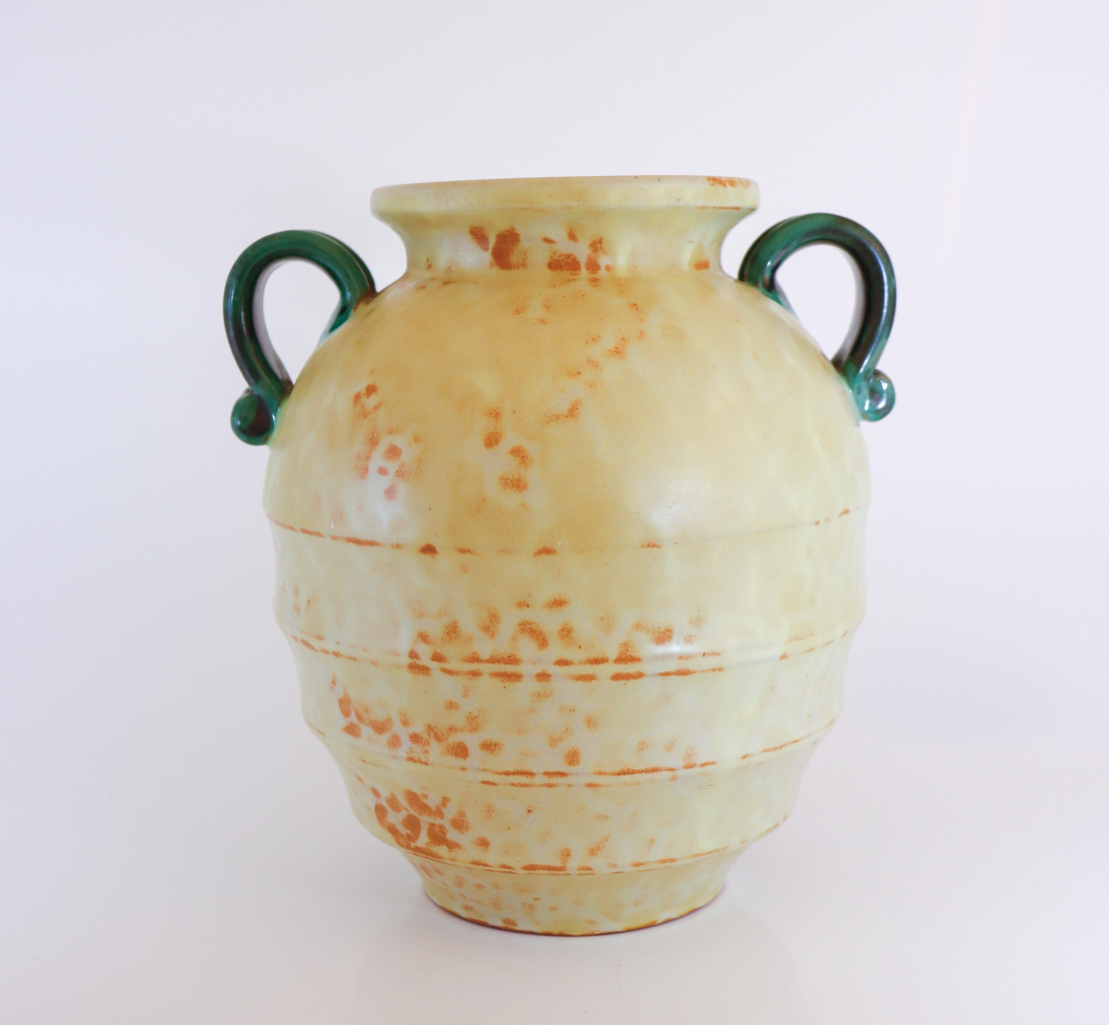 Ce magnifique vase en céramique beige avec des poignées en forme d'urne romaine classique a été conçu par Harald Östergren à Upsala Ekeby entre 1937 et 1938. Il mesure 21 cm de haut et environ 17 cm de diamètre. Il est en excellent état, à