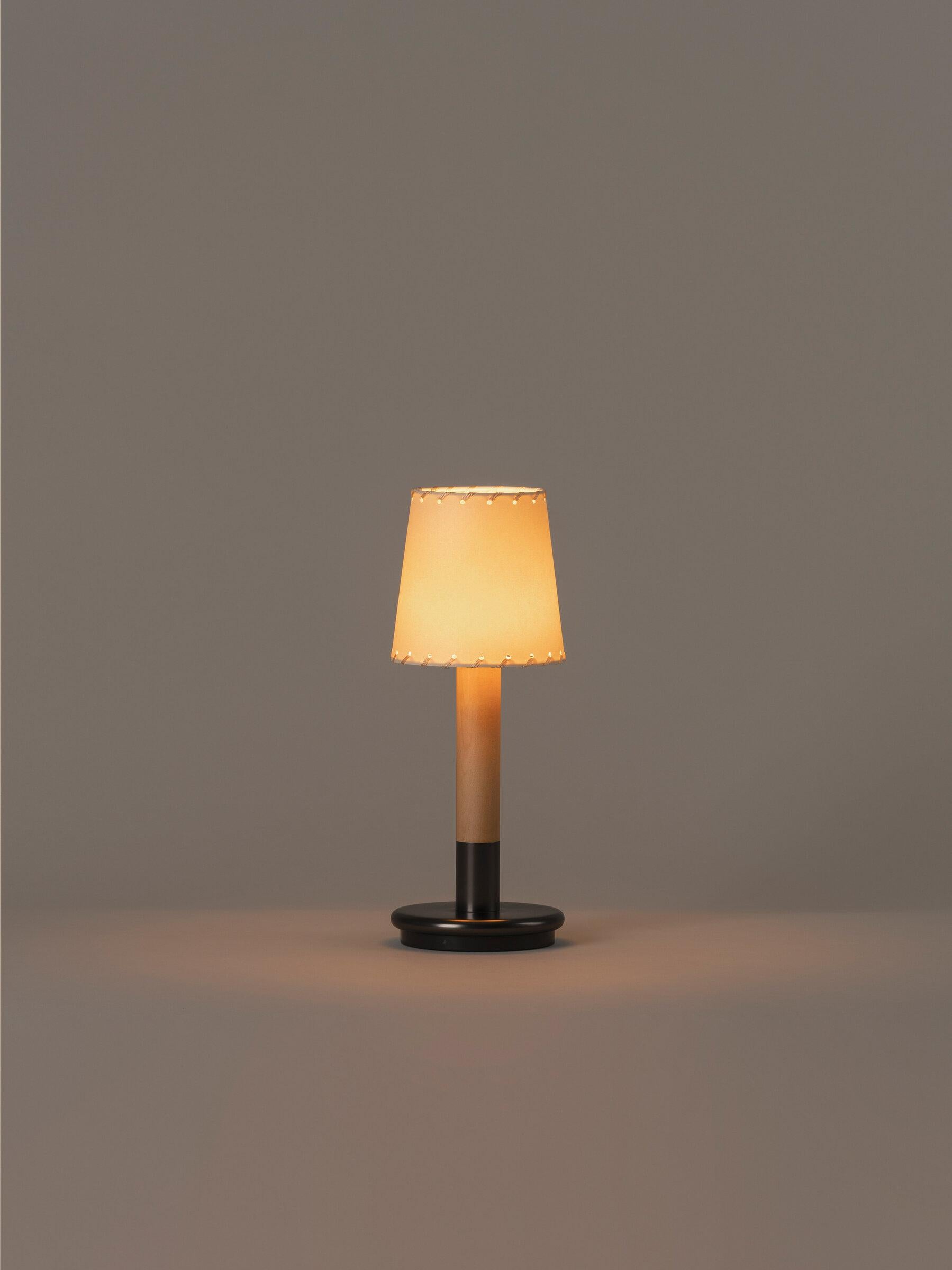 Beige Básica Mínima Batería table lamp by Santiago Roqueta, Santa & Cole.
Dimensions: D 12.7 x H 33 cm.
Materials: Bronze, birch wood, stitched parchment.
Available in other lampshade.

Básica Mínima Batería is the portable version of Básica