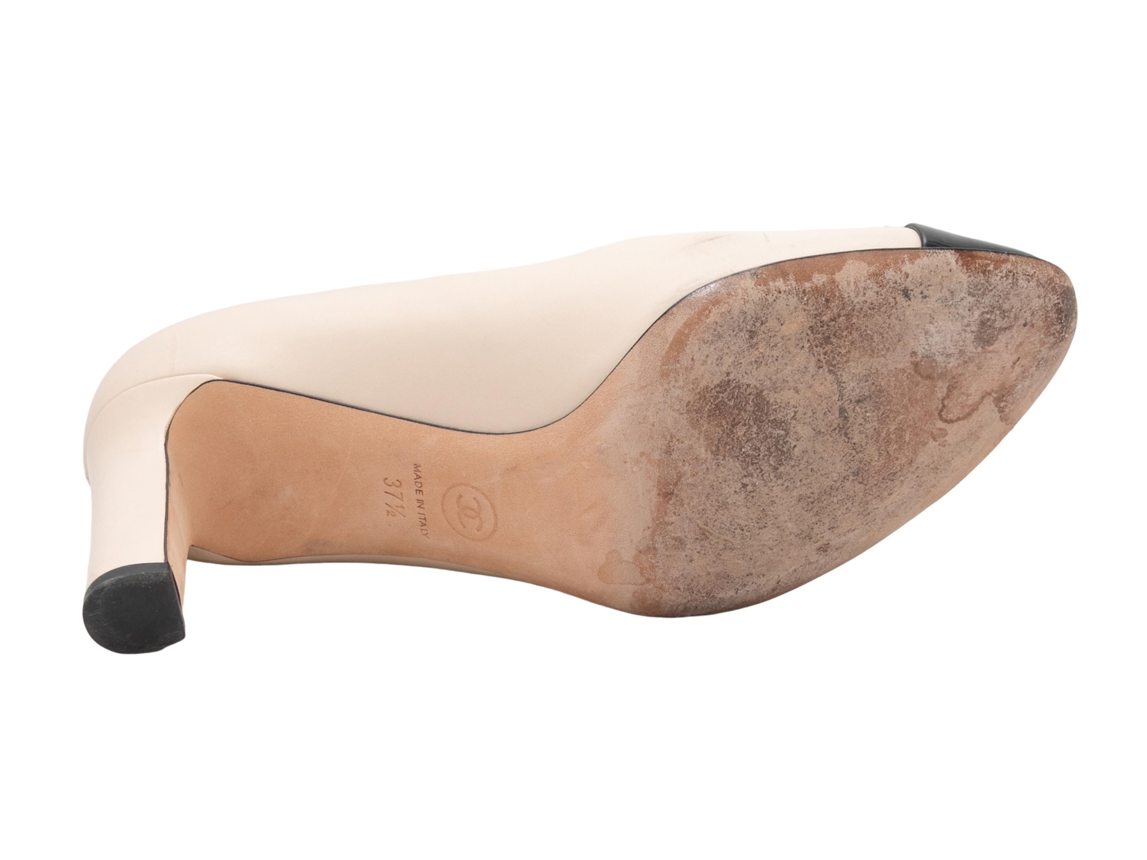 Beige and black leather and patent leather cap-toe pumps by Chanel. CC logo embroidery at tops. 3.25
