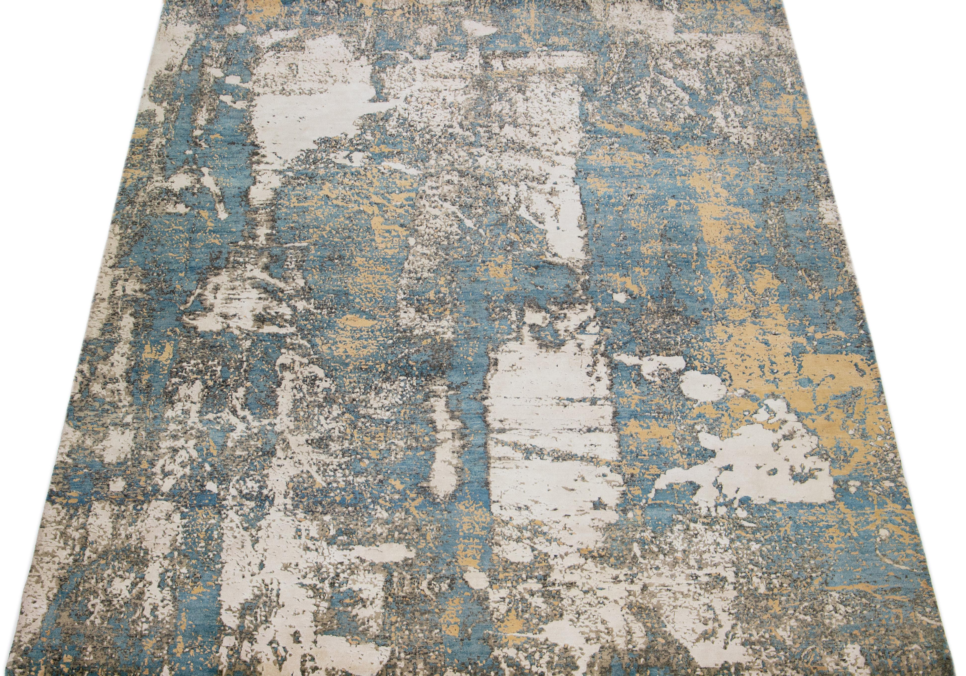 Beautiful modern Tibetan Indian wool & silk rug with a beige field in an abstract patterning blue, gray, and tan color. This combination of materials offers strength and durability for everyday use, and its intricate design adds a touch of elegance