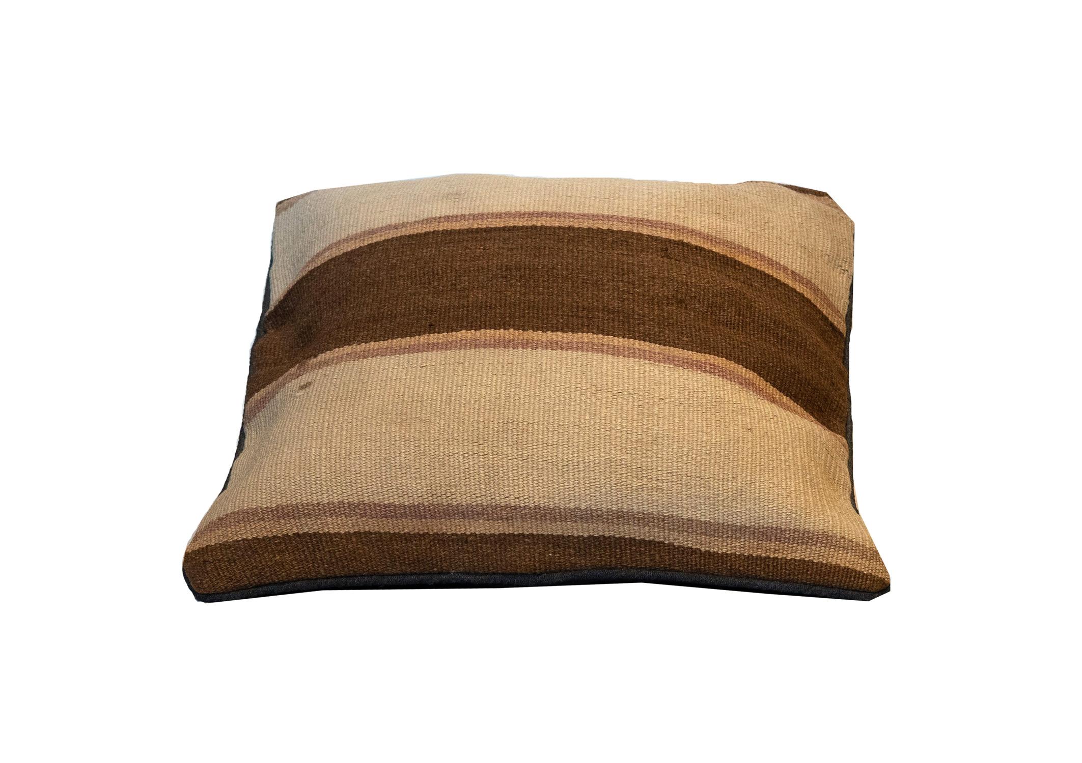 This simple cushion has been woven by hand using traditional kilim weaving techniques with hand-spun wool. Featuring a simple stripe design, with thick cream and brown lines, with smaller beige and subtle pink lines. With some small signs of age.