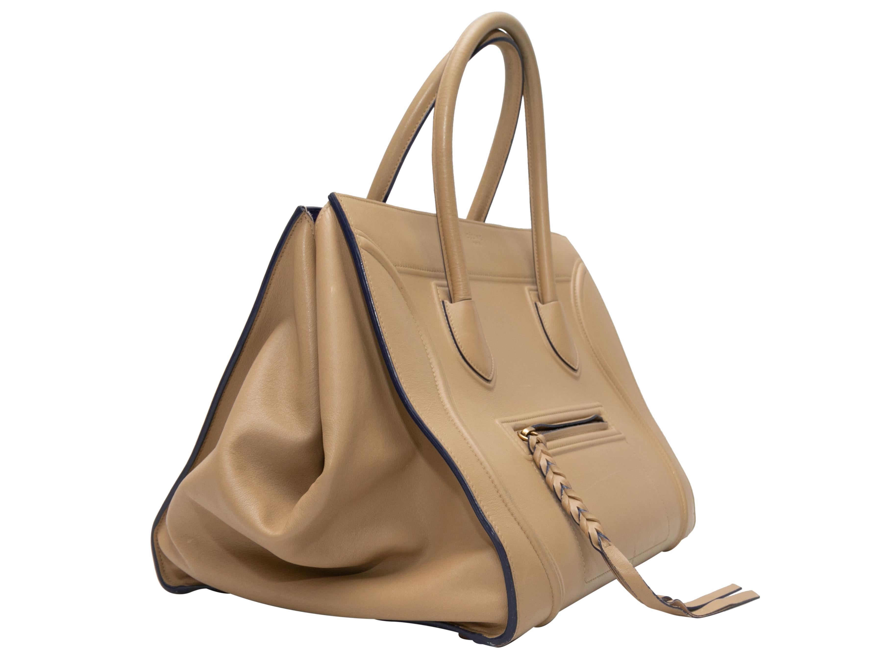 Beige Celine Medium Phantom Luggage Bag. The Medium Phantom Luggage Bag features a leather body, dual rolled top handles, an exterior front zip pocket, and a royal blue suede interior. 12