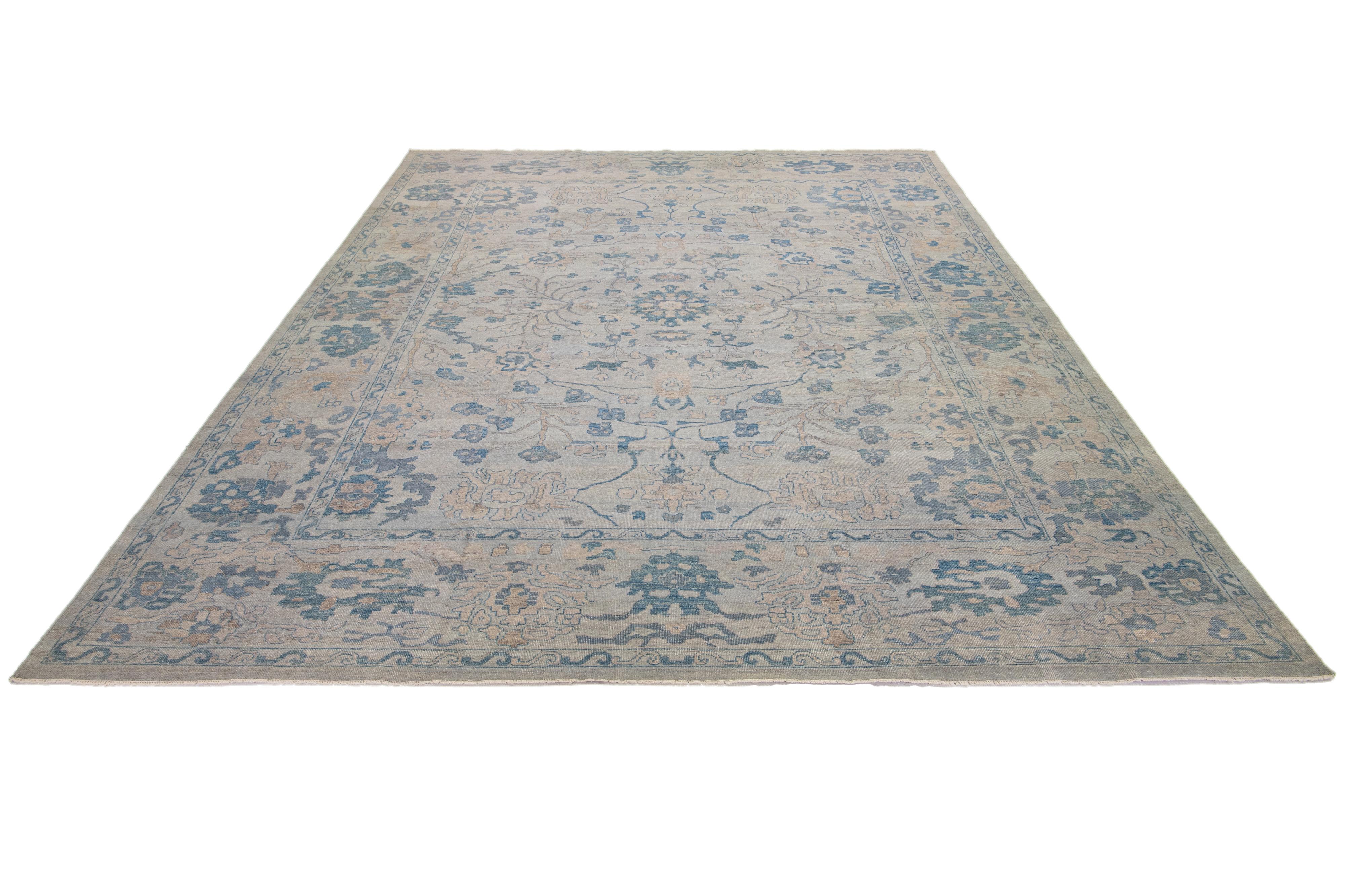 This Oushak rug is hand-knotted with a gray field. This mid-century modern-style rug has an all-over blue and brown floral design. 

This rug measures 11'10