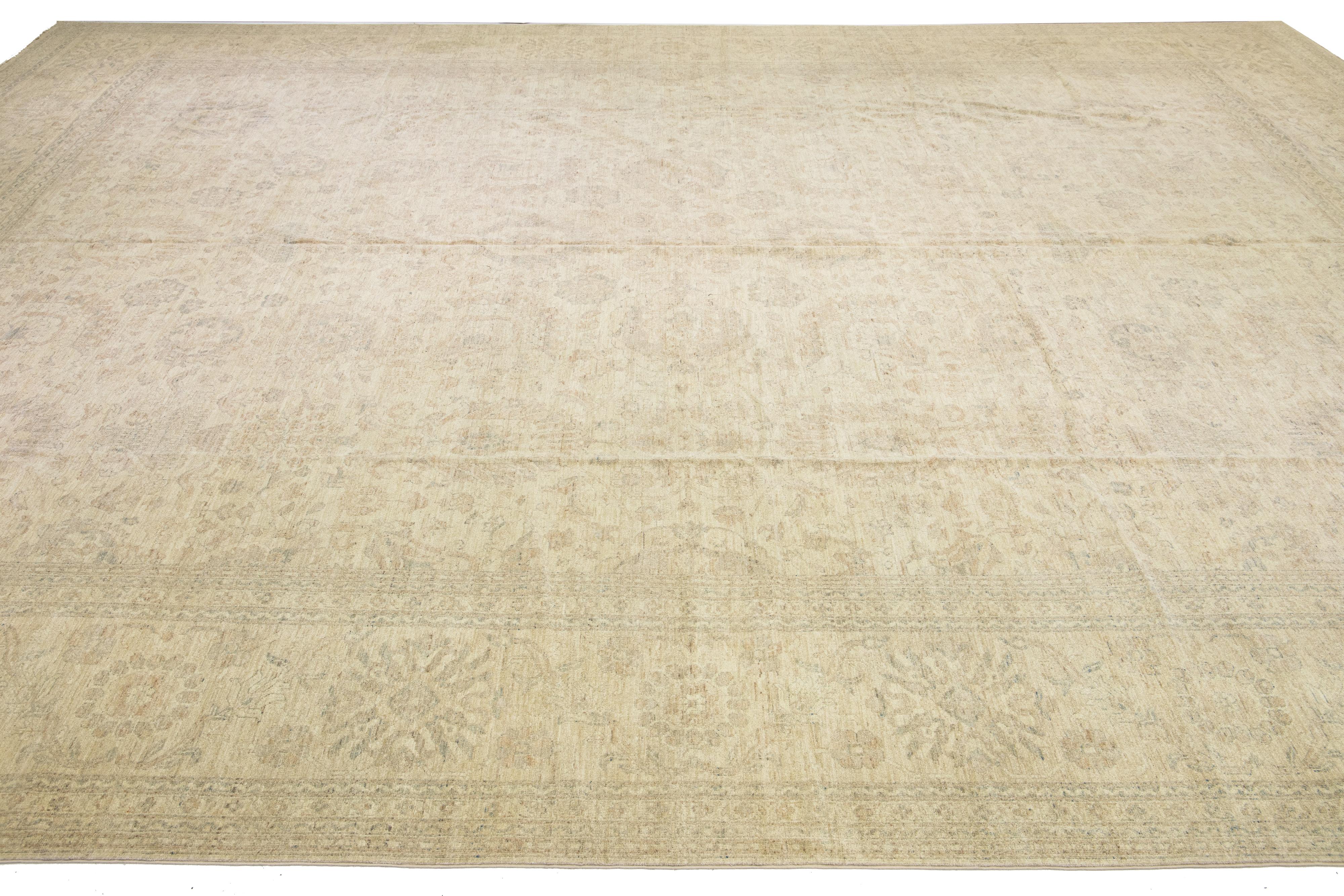 This remarkable contemporary Indian wool rug boasts a magnificent palace size, adorned with a warm beige field and intricate blue floral motifs. Its impressive dimensions measure 17' 9” x 22' 5”, perfect for adding a touch of elegance and