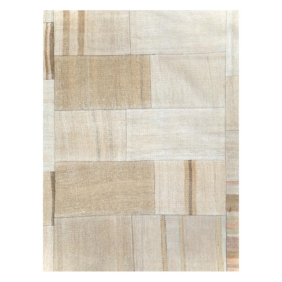 A contemporary Turkish flatweave Kilim accent rug handmade during the 21st century in shades of beige, cream, and brown. This patchwork style rug consists of hand-weaving together several remnants of vintage Kilim carpets from the mid-20th century
