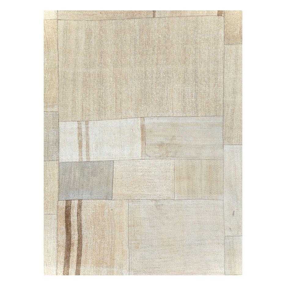 A contemporary Turkish flatweave Kilim small room size carpet handmade during the 21st century in shades of beige, cream, and brown. This patchwork style rug consists of hand-weaving together several remnants of vintage Kilim carpets from the