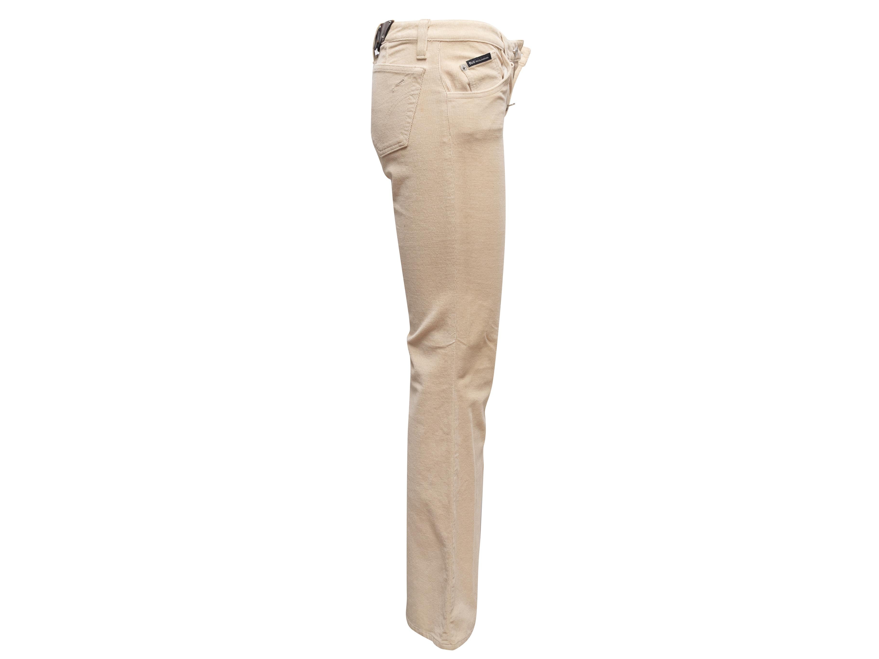 Pantalon bootcut beige en velours côtelé D&G. Cinq poches. Boucle en cuir marron à l'arrière de la ceinture. Fermeture à glissière et bouton sur le devant. Taille 26