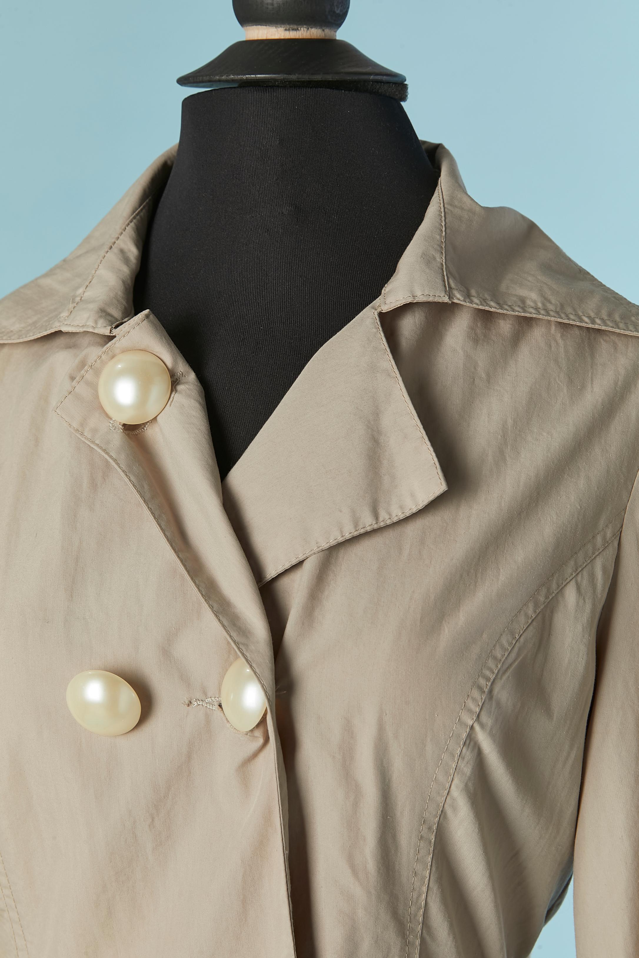 Beige double breasted trench-coat with ruffles on the bottom. 
Main fabric composition: 80% cotton, 20% burlap. Satin lining. Fabric belt which can be tied on the front or on the back. 
Button and buttonhole closure on the front. Button on the cuffs