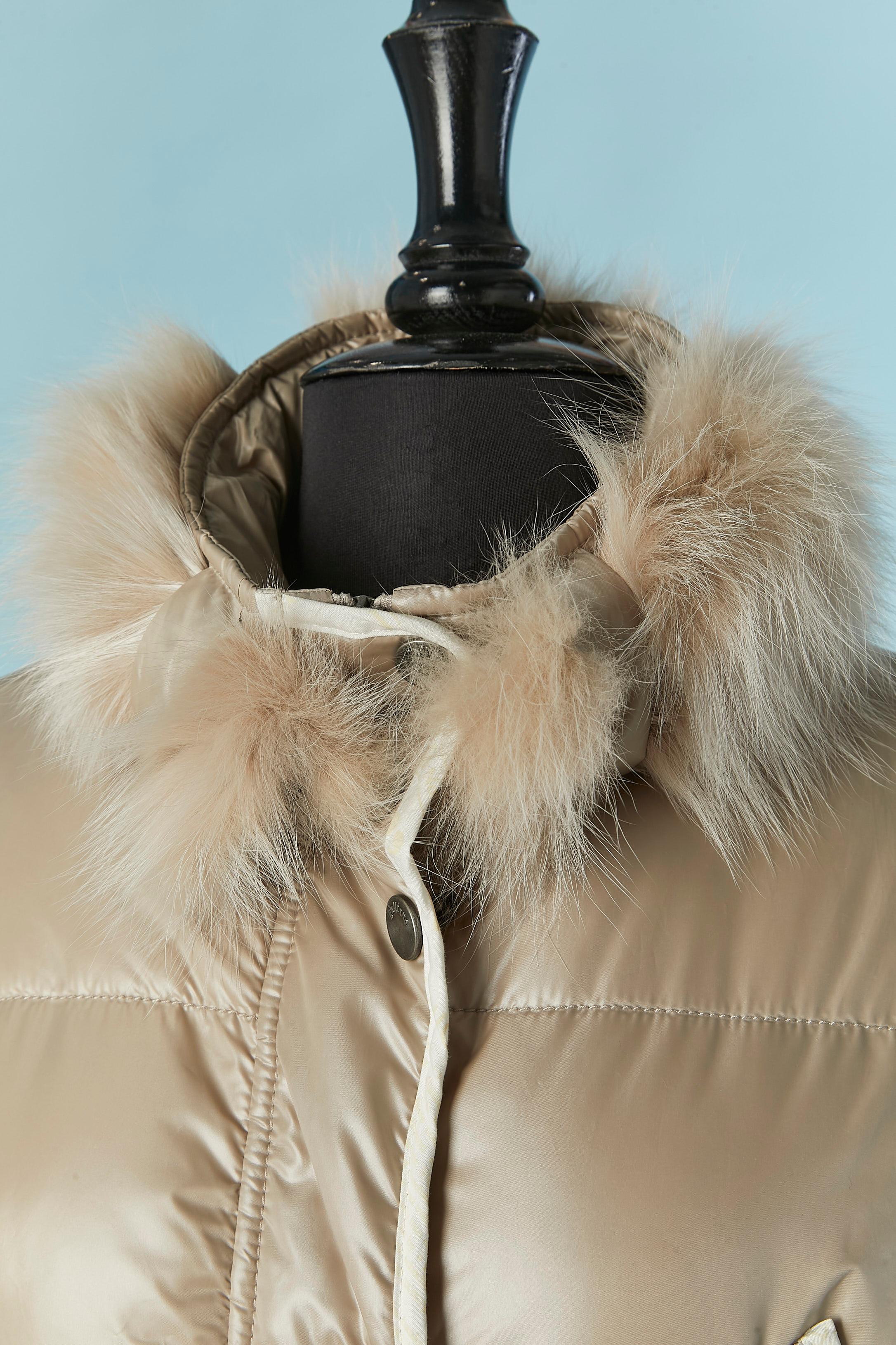 Beige down jacket with fox fur collar. The fur is detachable with snap.Outside fabric composition: 100% polyester. Branded and Gazette pattern lining composition : Elite & Polyester. Padding: 100% polyester. 
Branded snap closure on the middle front