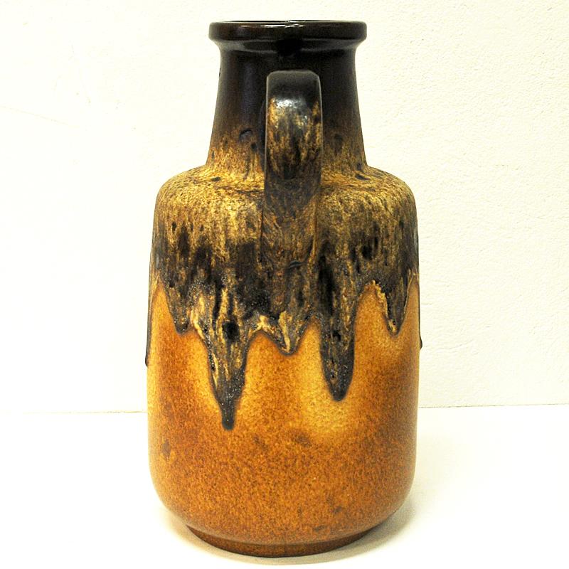 This large jug-handled vintage vase was produced under the 1970s by Scheurich, West Germany. It is brown at the top with an earth coloured circle motive around the body. Fat Lava style painting on a yellow base and floating brown color over matte