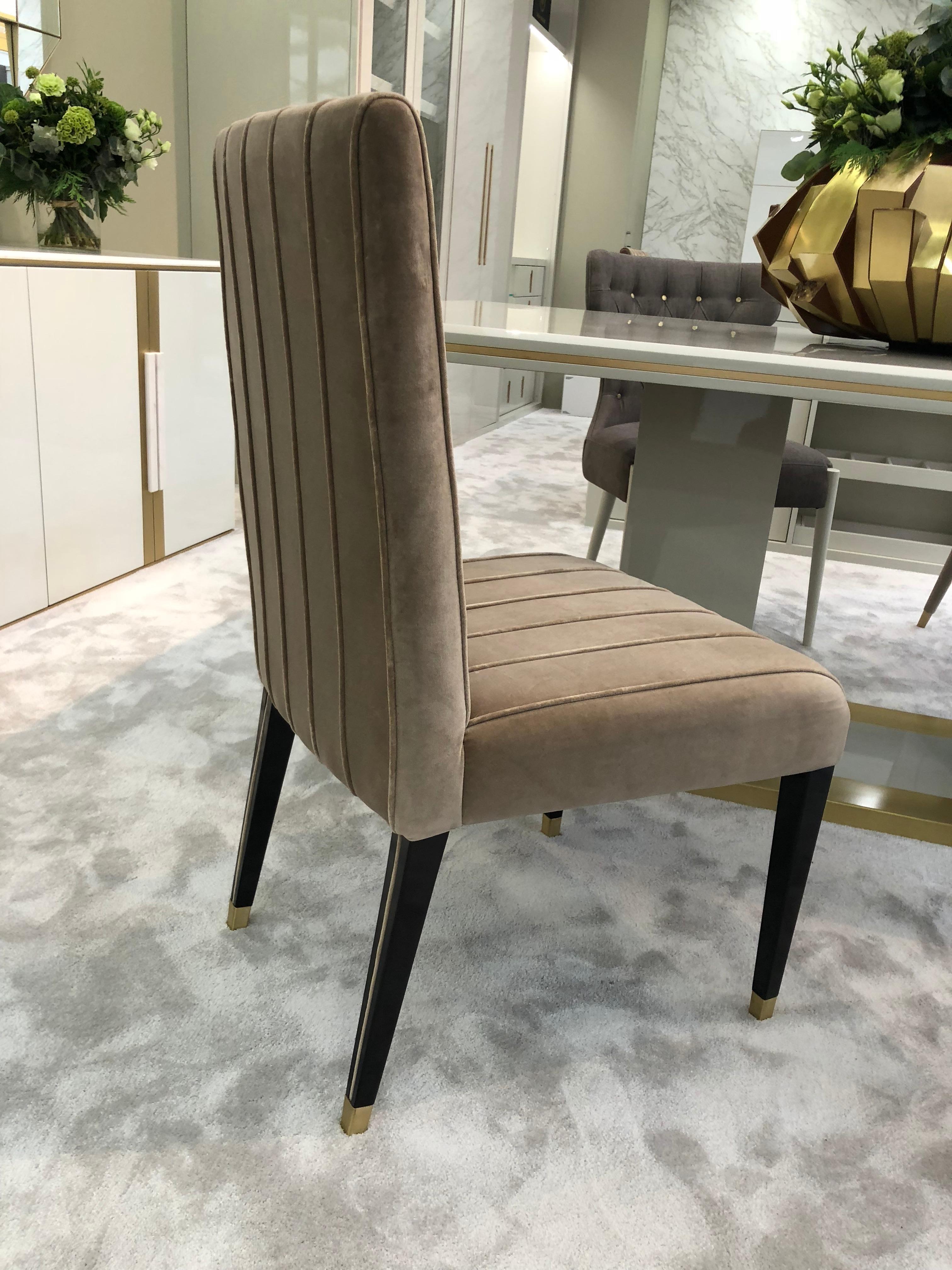 Intemporal dining chair, with beautiful detailled legs and trimms in fabric.
Upholstered in velvet Comfort 05 , combined with glossy lacquered legs in CM7 colour (dark brown) and brushed brass tips.