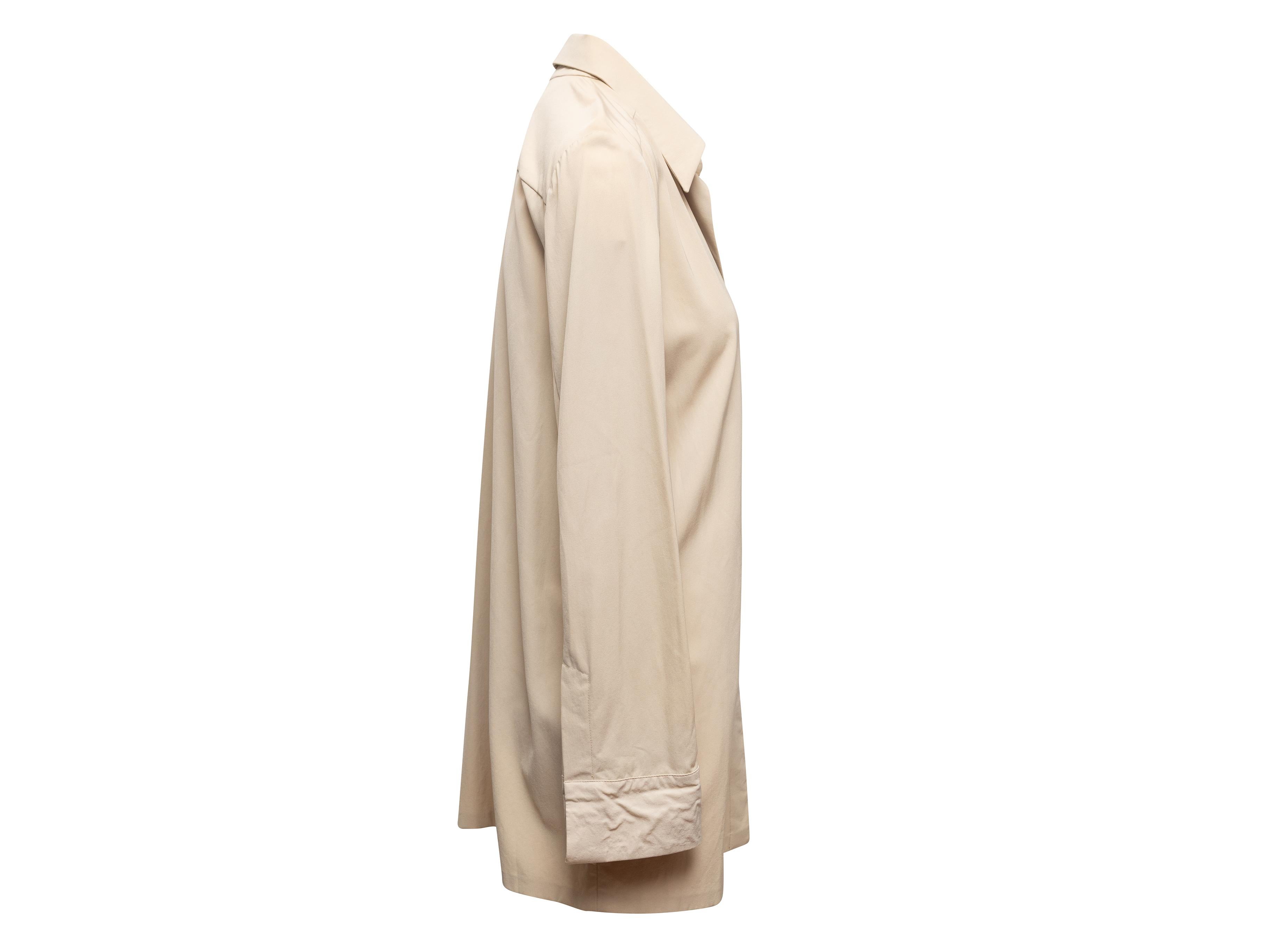 Top boutonné beige à manches longues, signé Gucci. Col pointu. Fermeture à boutons cachés sur le devant. Poitrine de 44