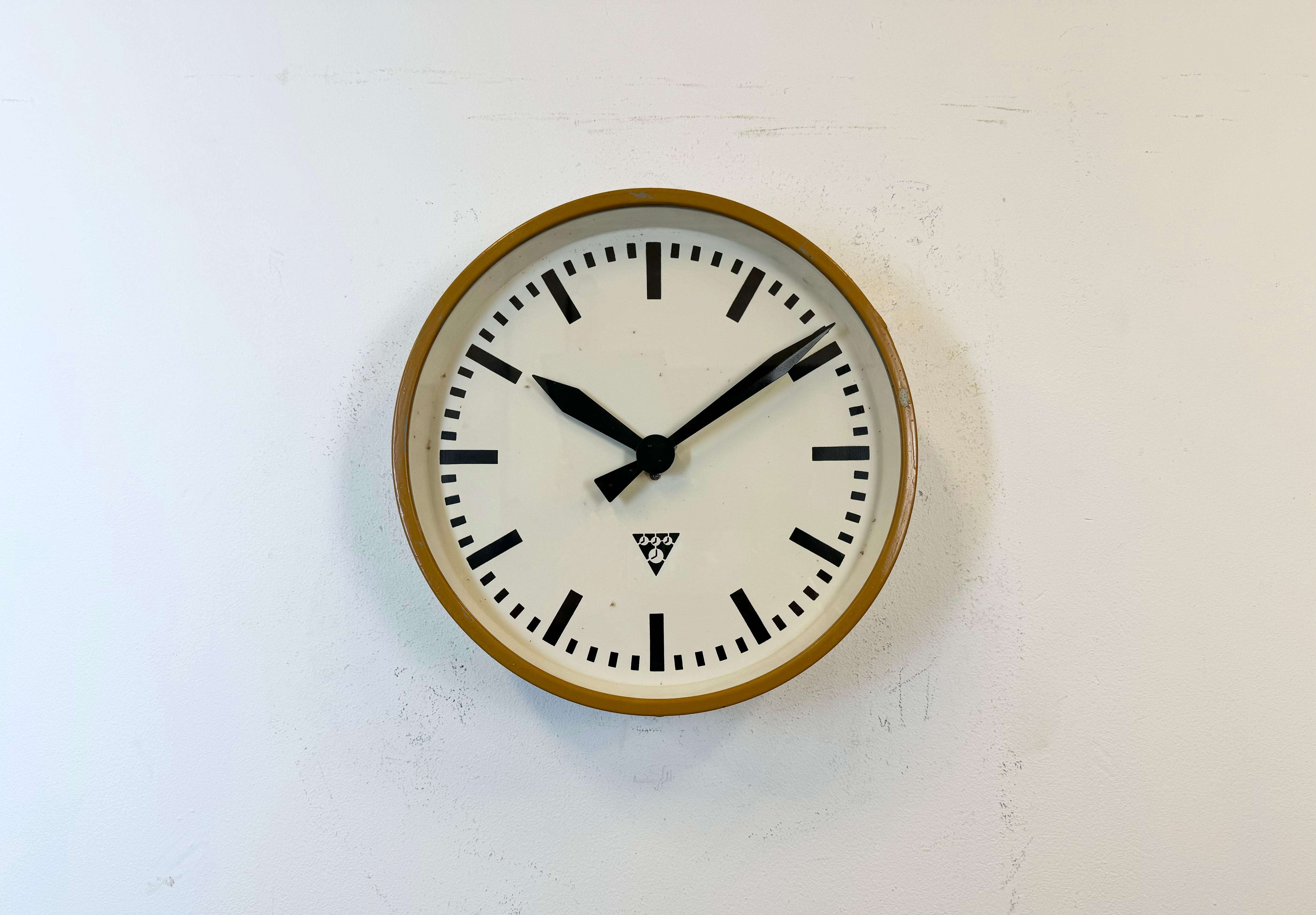This wall clock was produced by Pragotron in former Czechoslovakia during the 1960s. It features a beige metal frame, an iron dial, an aluminium hands and a clear glass cover. Former electric factory slave clock has been converted into a