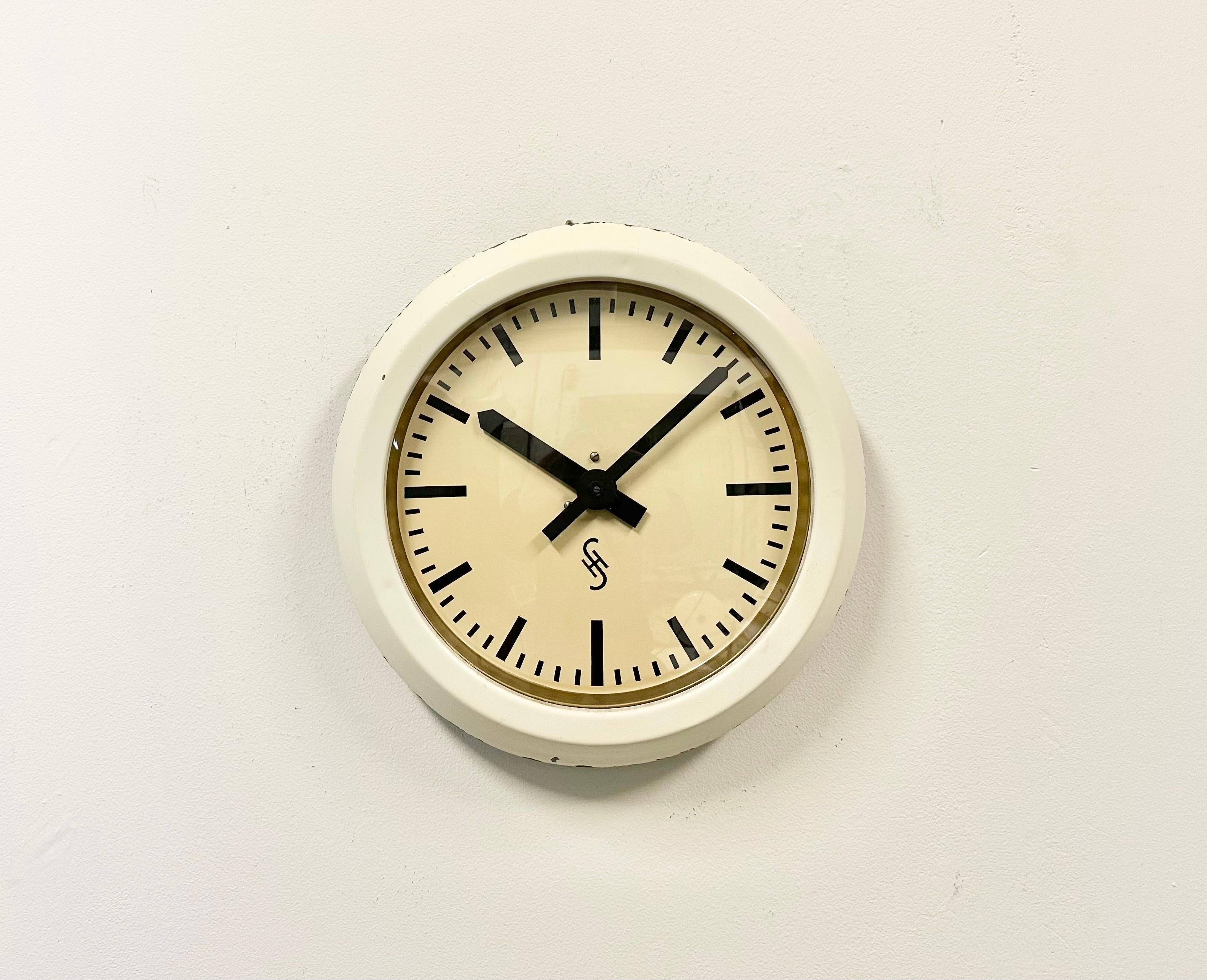This wall clock was produced by Siemens and Halske in Germany during the 1950s. It features a beige metal frame, aluminum dial, and a clear glass cover. The piece has been converted into a battery-powered clockwork and requires only one AA-battery.