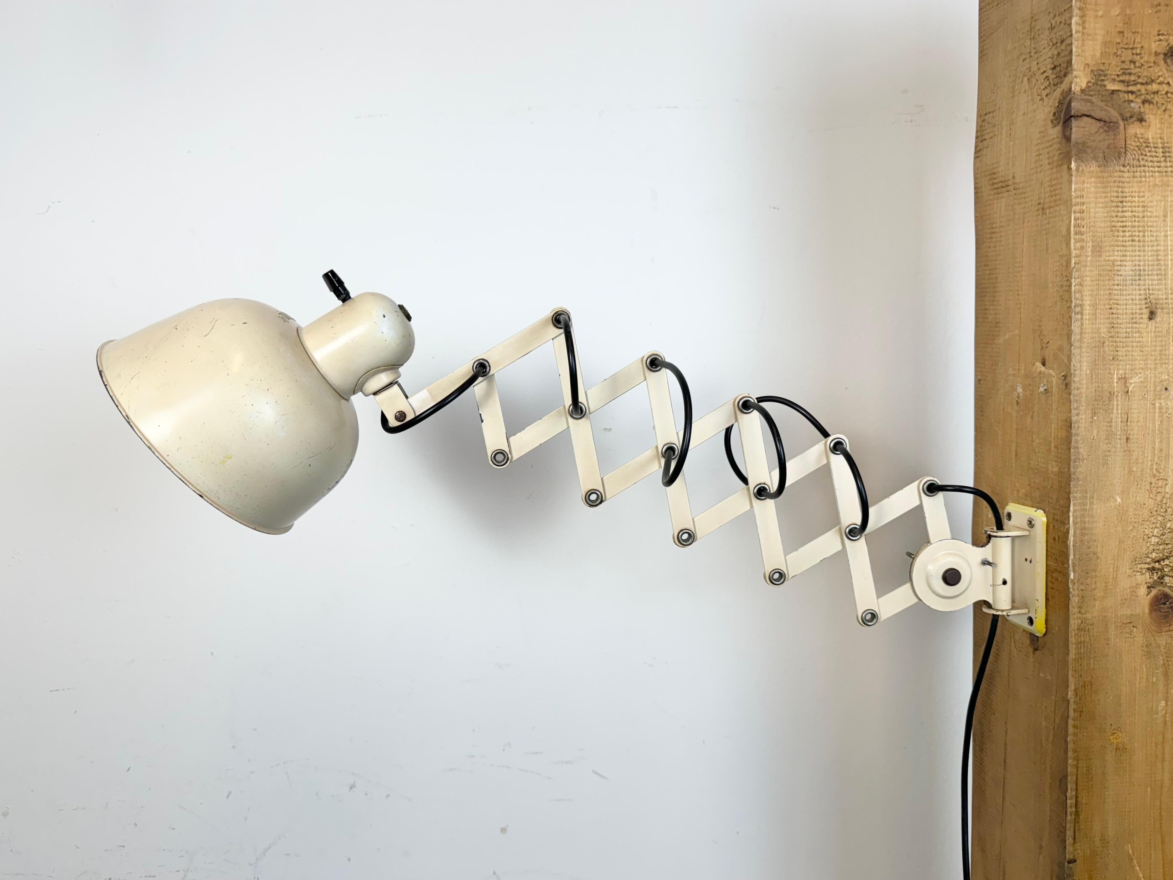 Industrial scissor wall lamp manufactured by Wila Leuchten in Germany during the 1960s. The lamp has a metal shade. The iron scissor arm is extendable and can be turned sideways. Original swich is situated directly on shade.The socket requires