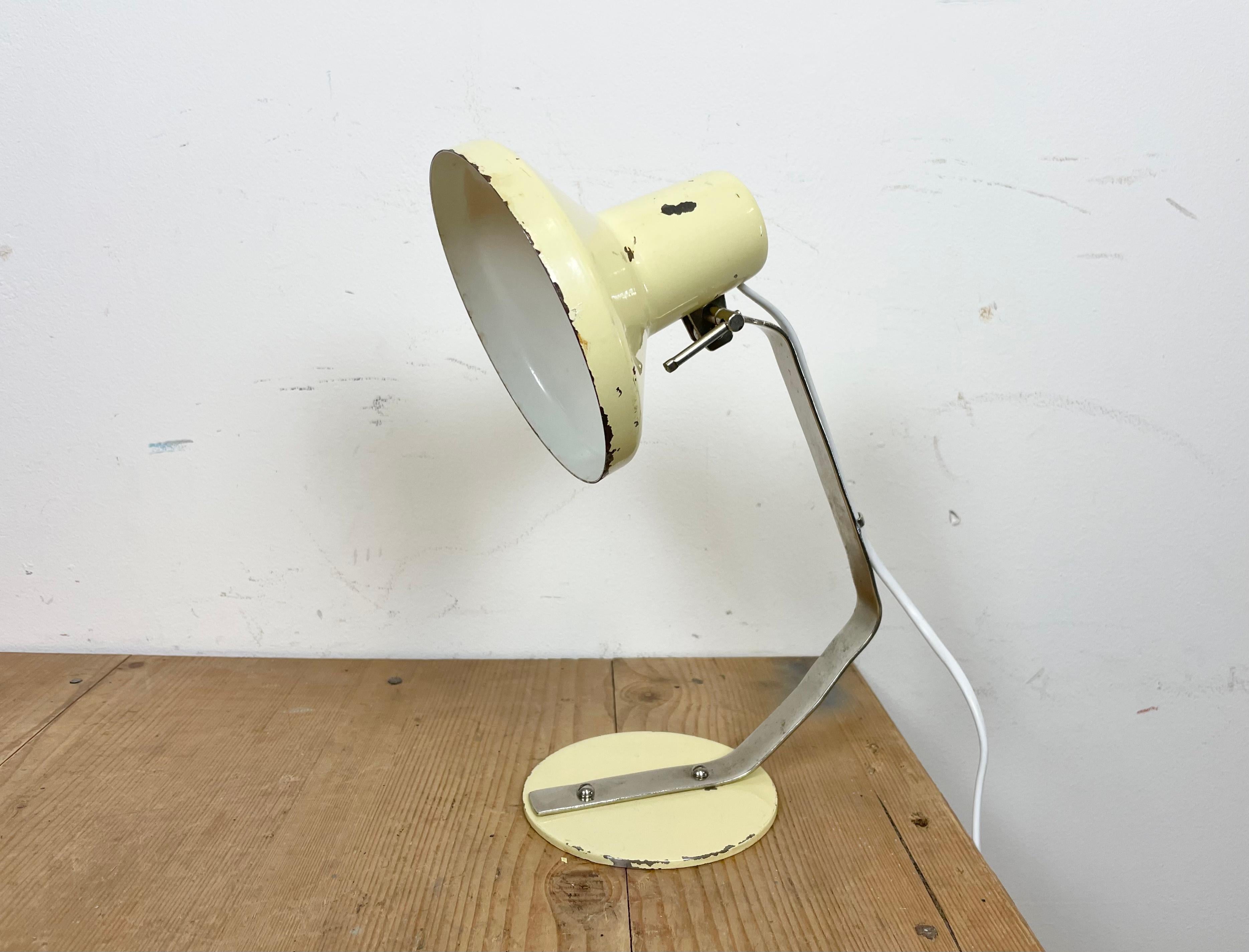 Lampada da tavolo industriale realizzata da Metal Mot in Polonia negli anni '60. Presenta una base beige, un paralume regolabile beige e un braccio cromato.L'attacco originale richiede lampadine E 14. Il peso della lampada è di 2 kg.
