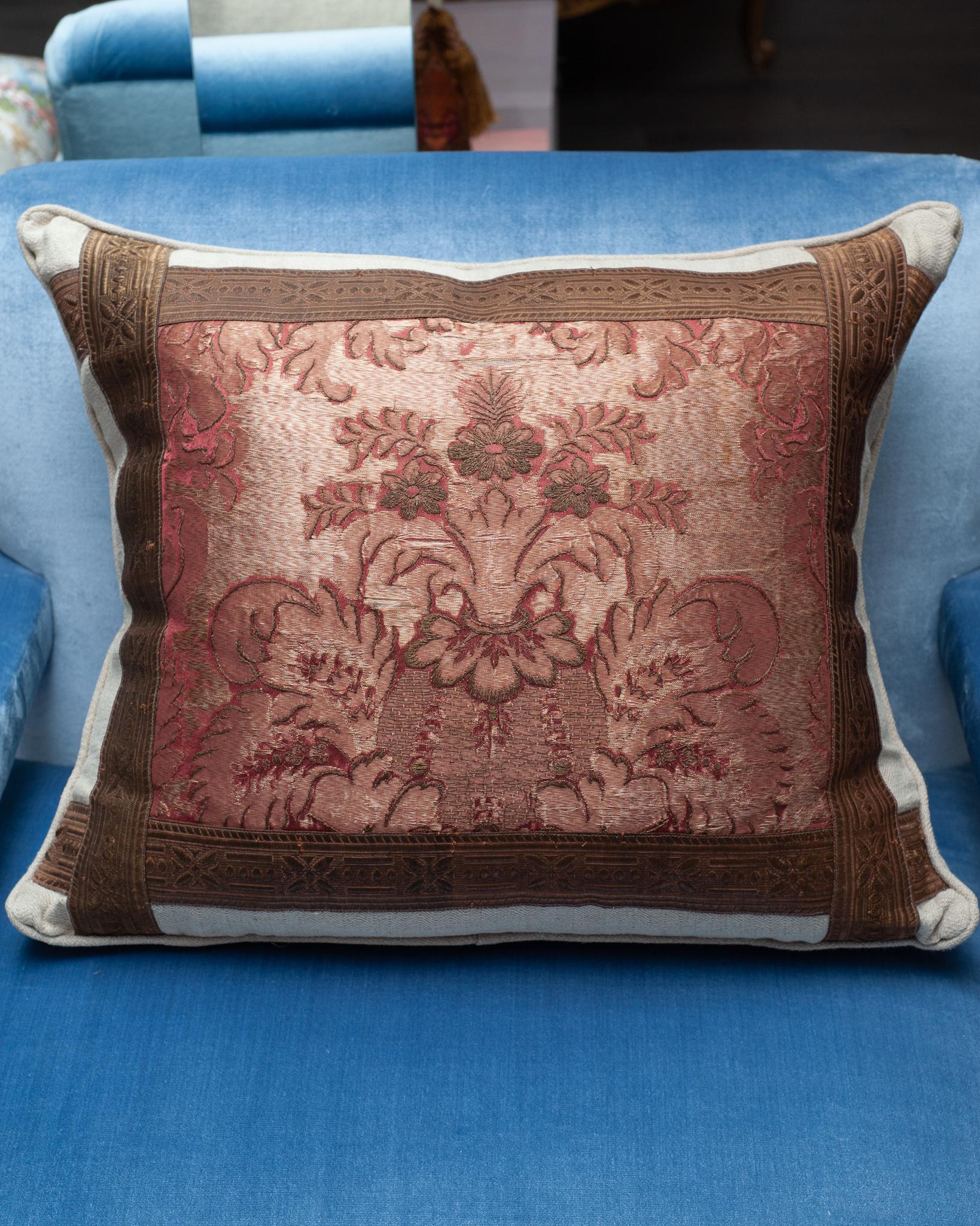 A beautiful beige linen pillow with front red antique embroidered panel and metallic trims. Filled with 100% Canadian down and feather insert.