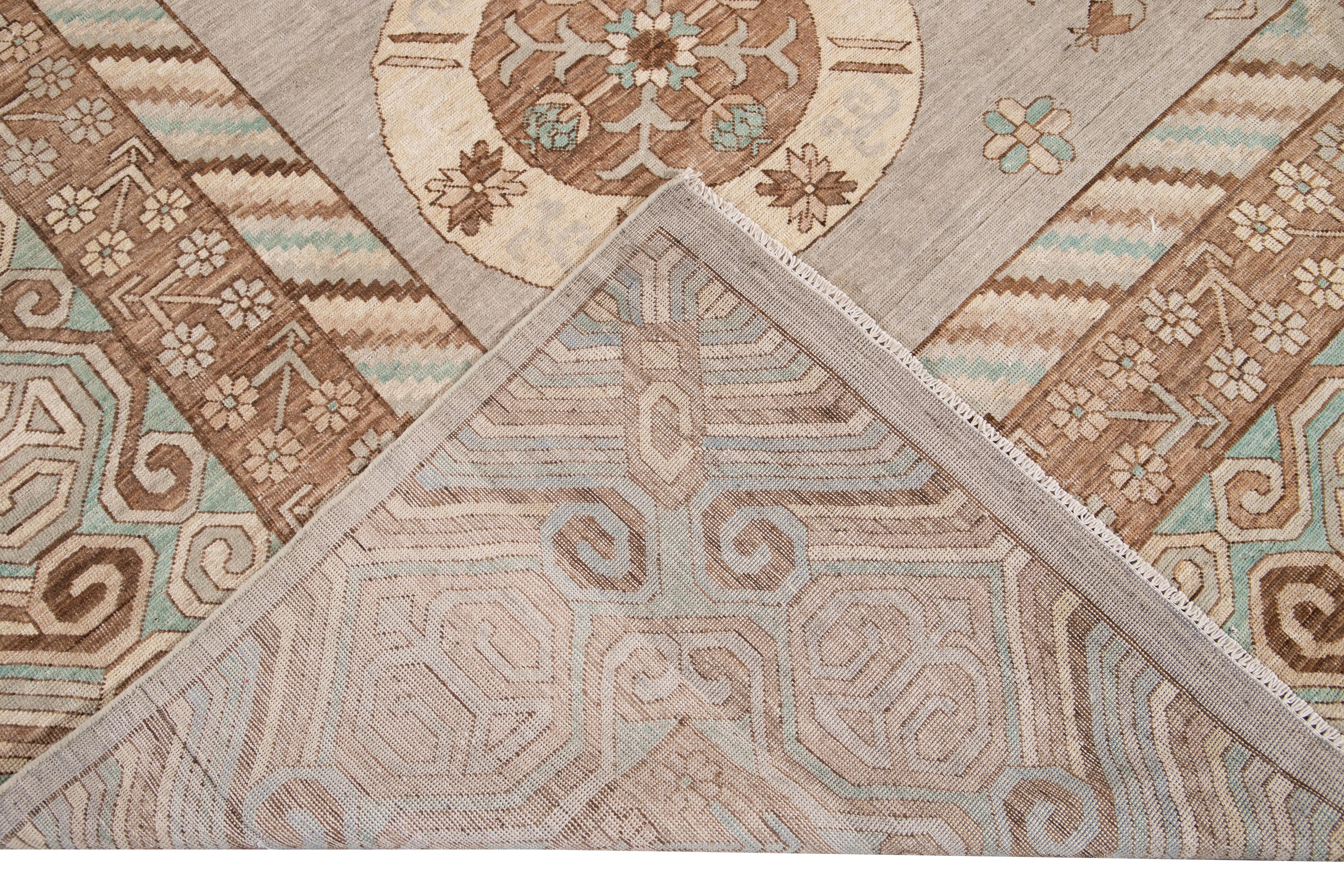 Beautiful Modern Khotan style hand knotted wool rug beige and gray field. This Khotan style rug has a beautifully designed frame and accents of turquoise and brown in a gorgeous all-over geometric medallion floral design,

This rug measures 11' 8