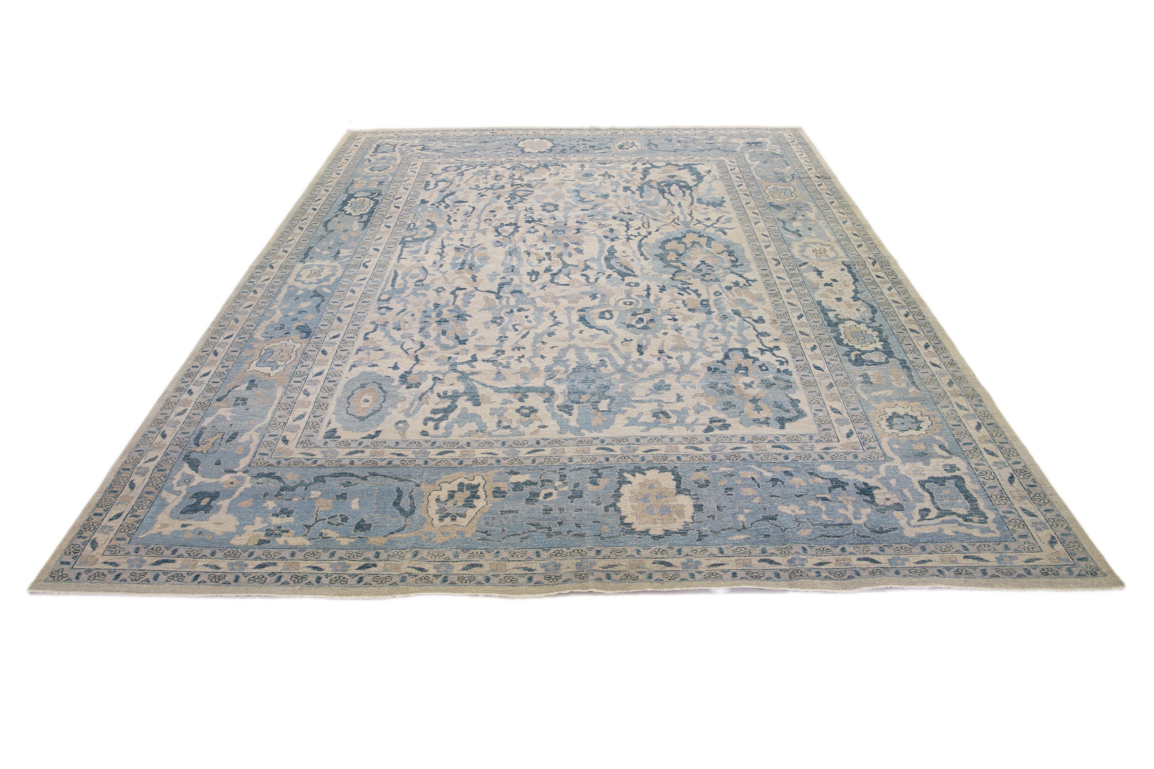 A Khotan wool rug In a beige color field with allover floral designs. This hand-knotted modern piece has blue accents that complement the design.

This rug measures 11'11