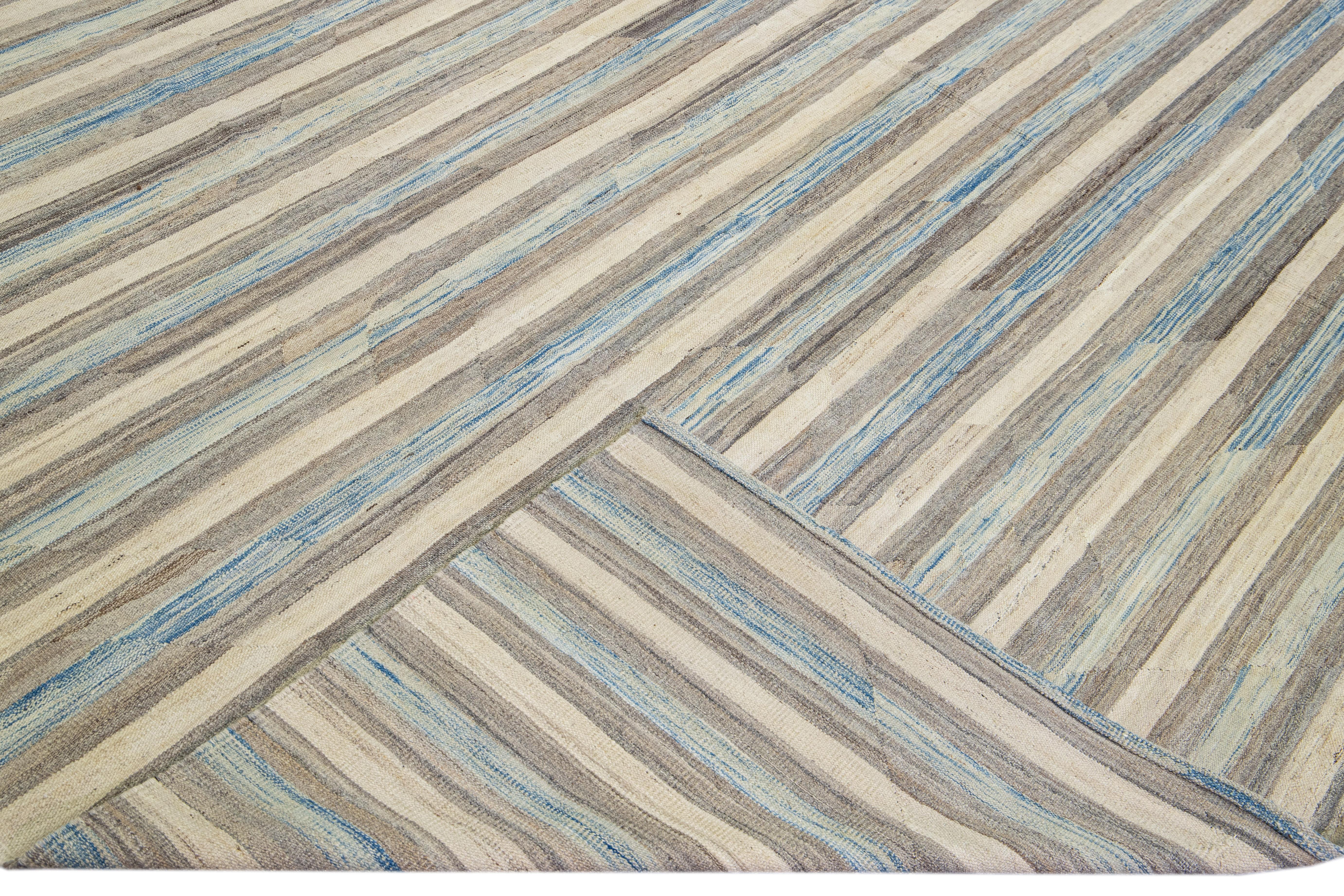Magnifique tapis Kilim moderne en laine tissé à plat, fait main, avec un champ beige. Ce tapis Kilim a des accents bleus et bruns dans un magnifique design expressionniste abstrait.

Ce tapis mesure : 13'2