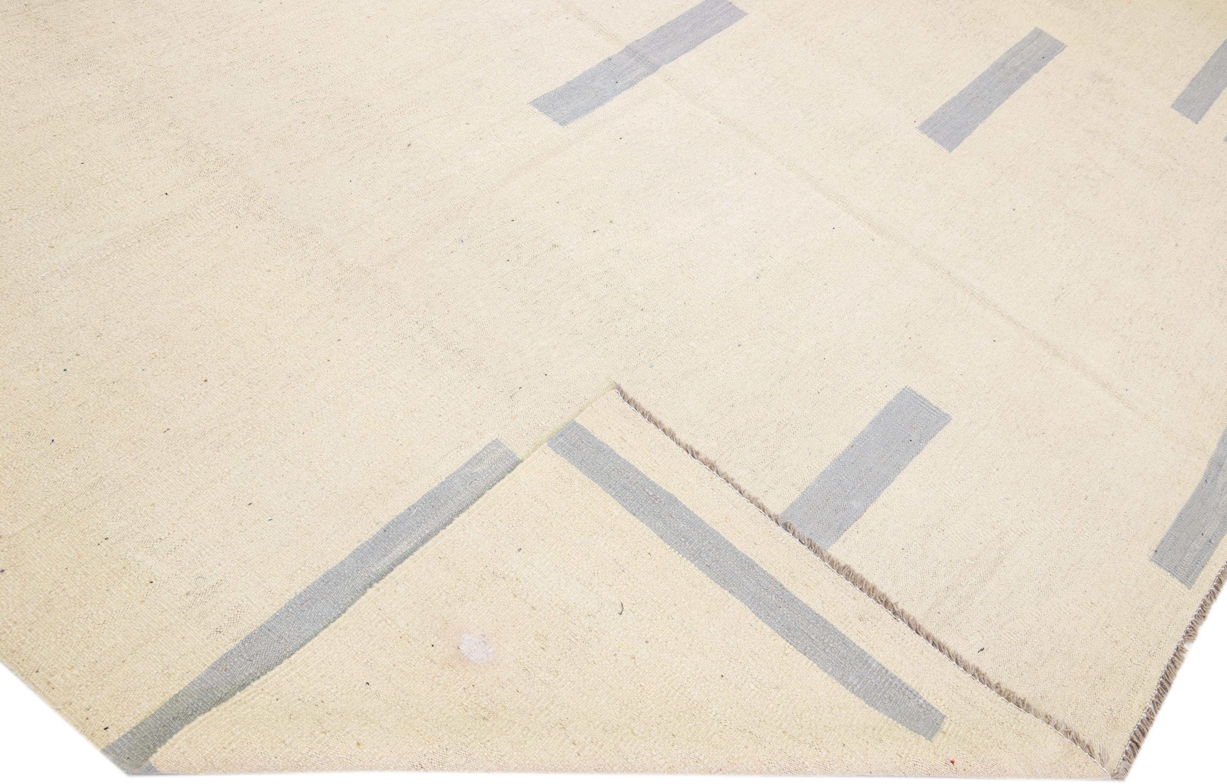 Magnifique tapis Kilim moderne en laine tissé à plat, fait main, avec un champ de couleur beige. Ce tapis Kilim a des accents gris dans un magnifique design géométrique.

Ce tapis mesure : 10'3