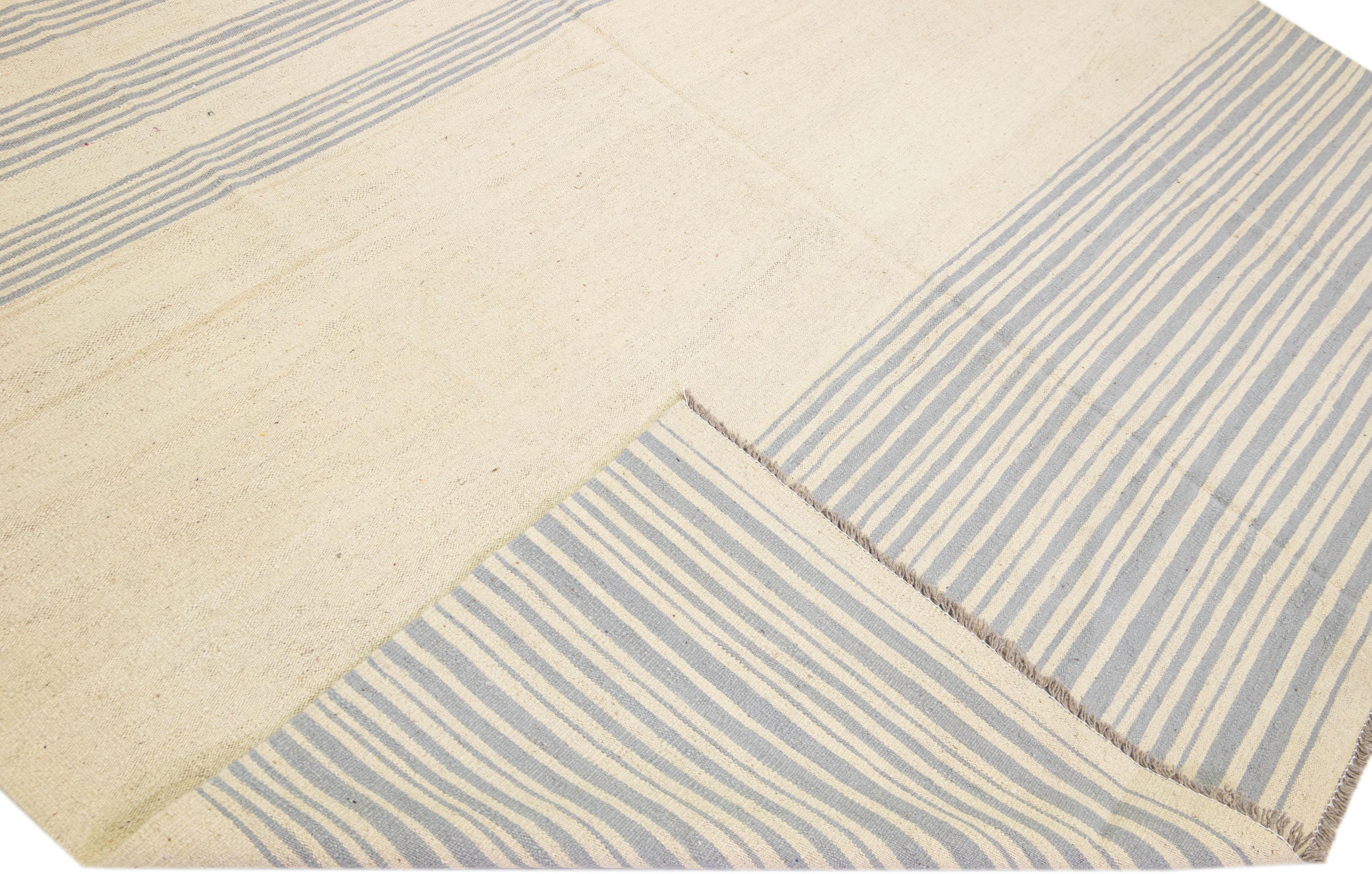 Schöner moderner flachgewebter Kilim-Teppich aus handgefertigter Wolle mit einem beigen Farbfeld. Dieser Kilim-Teppich hat graue Akzente in einem wunderschönen Streifendesign.

Dieser Teppich misst: 9'1