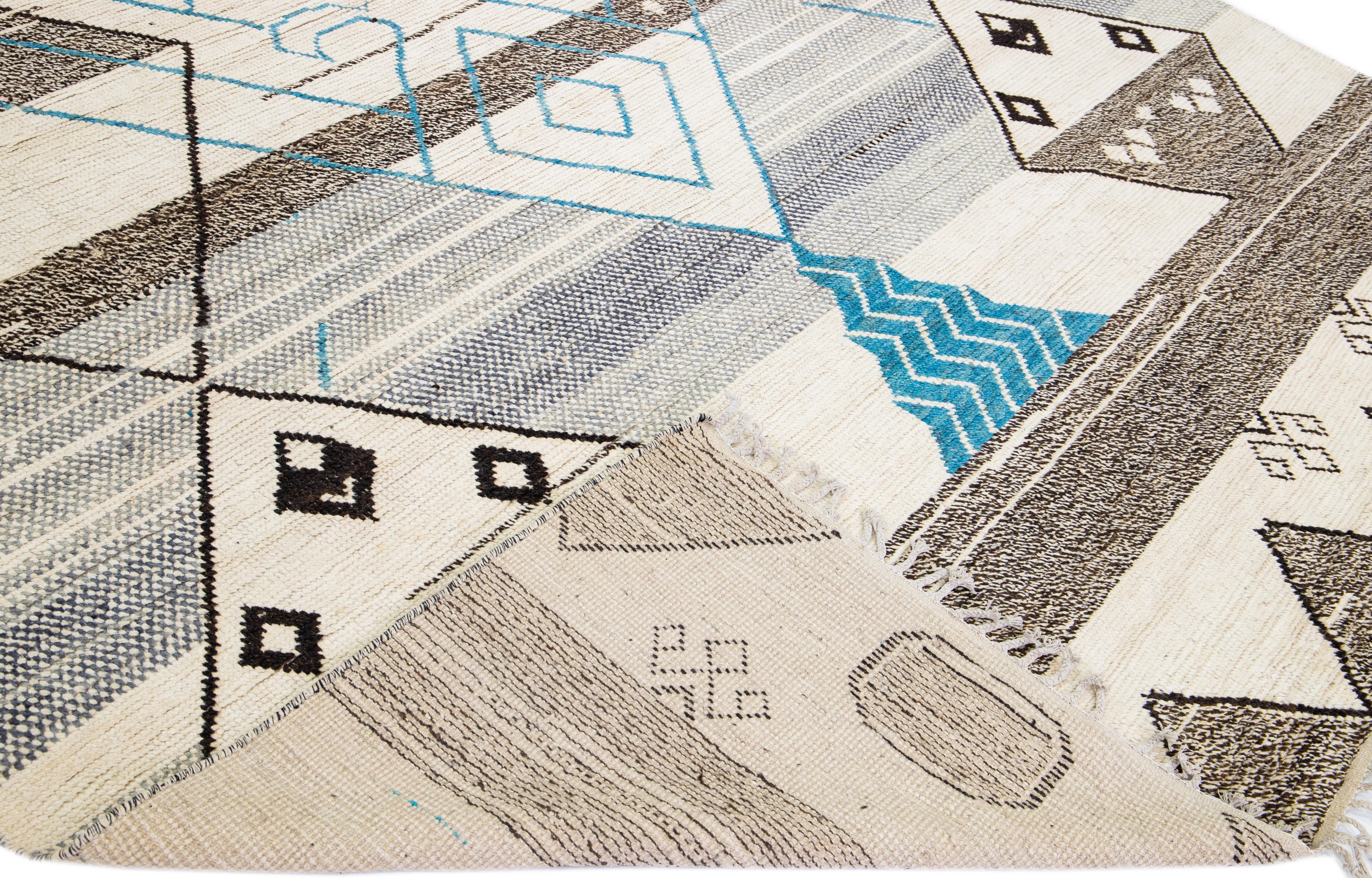 Magnifique tapis moderne de style marocain en laine nouée à la main avec un champ beige. Cette pièce a des accents gris, bruns et bleus dans un magnifique motif tribal avec des franges sur les extrémités supérieure et inférieure.

Ce tapis mesure