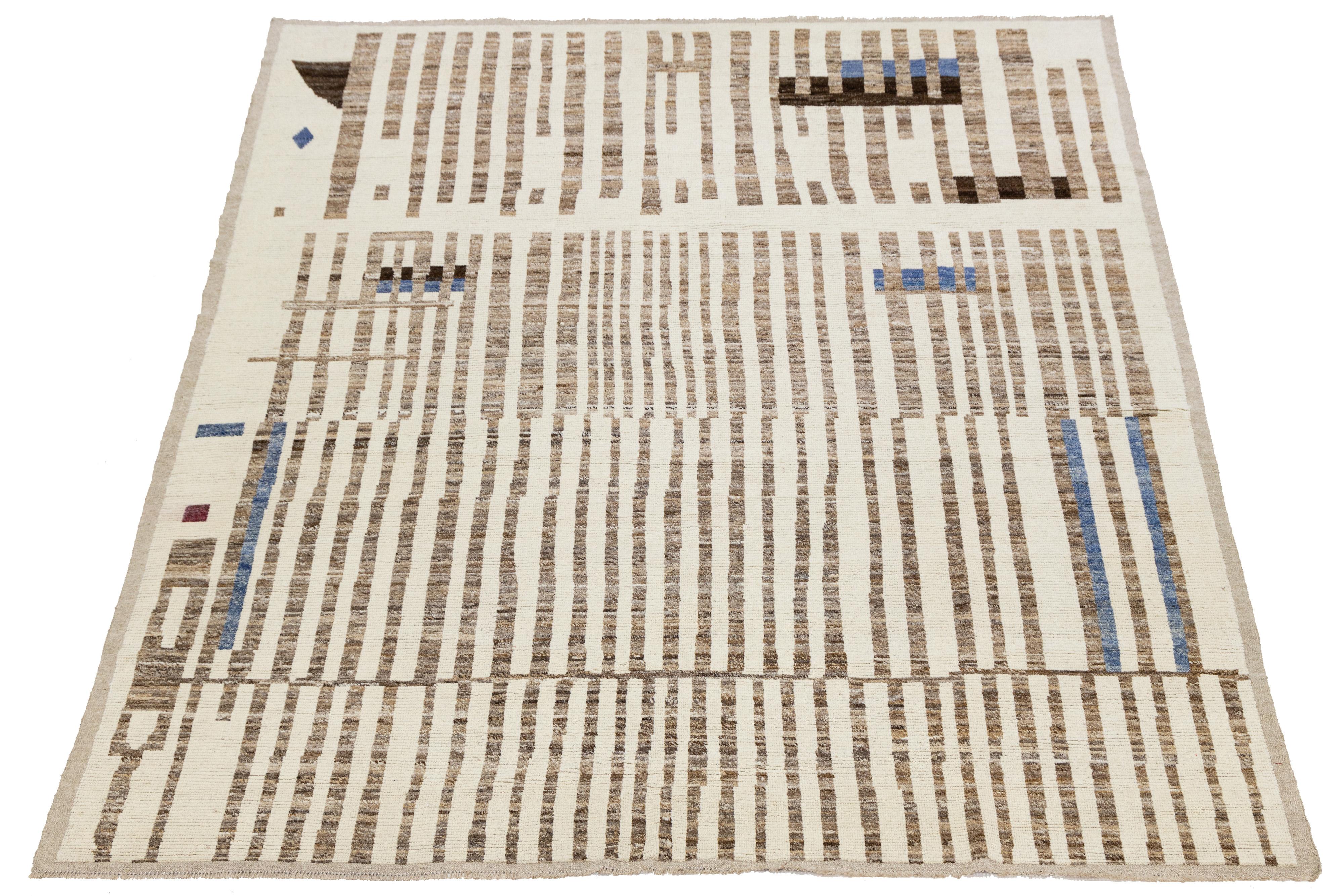 A striking modern Moroccan-style wool rug featuring vertical brown stripes and playful color blocks in blue, maroon, and black on a cream ground. Handwoven with a minimalist yet artistic sensibility, this piece blends traditional craftsmanship with