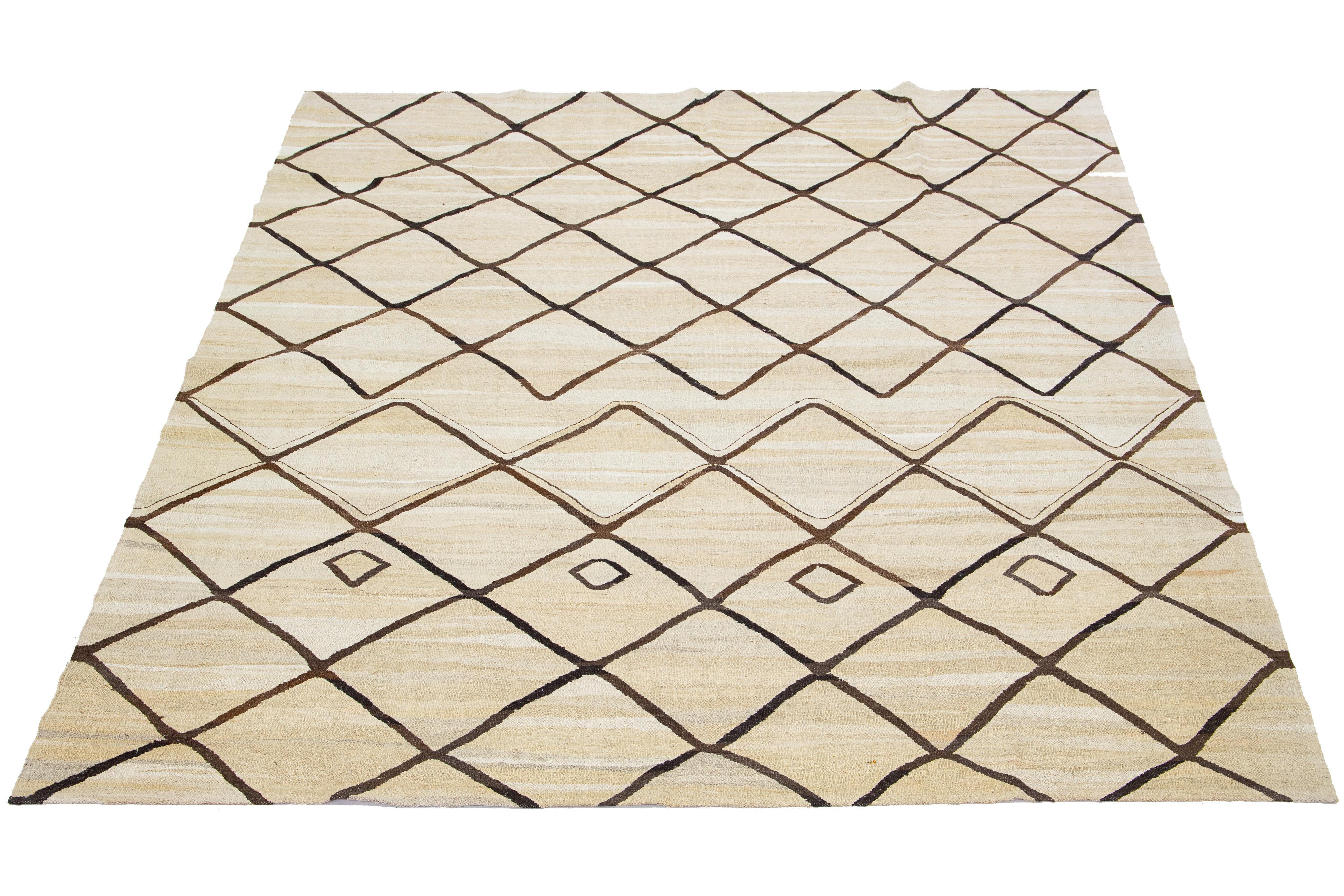 Dieser handgeknüpfte, moderne, flachgewebte Kilim-Wollteppich ist wunderschön gearbeitet. Es besteht aus einem beigen Feld mit einem geometrischen Muster in Braun.

Dieser Teppich misst 8'7