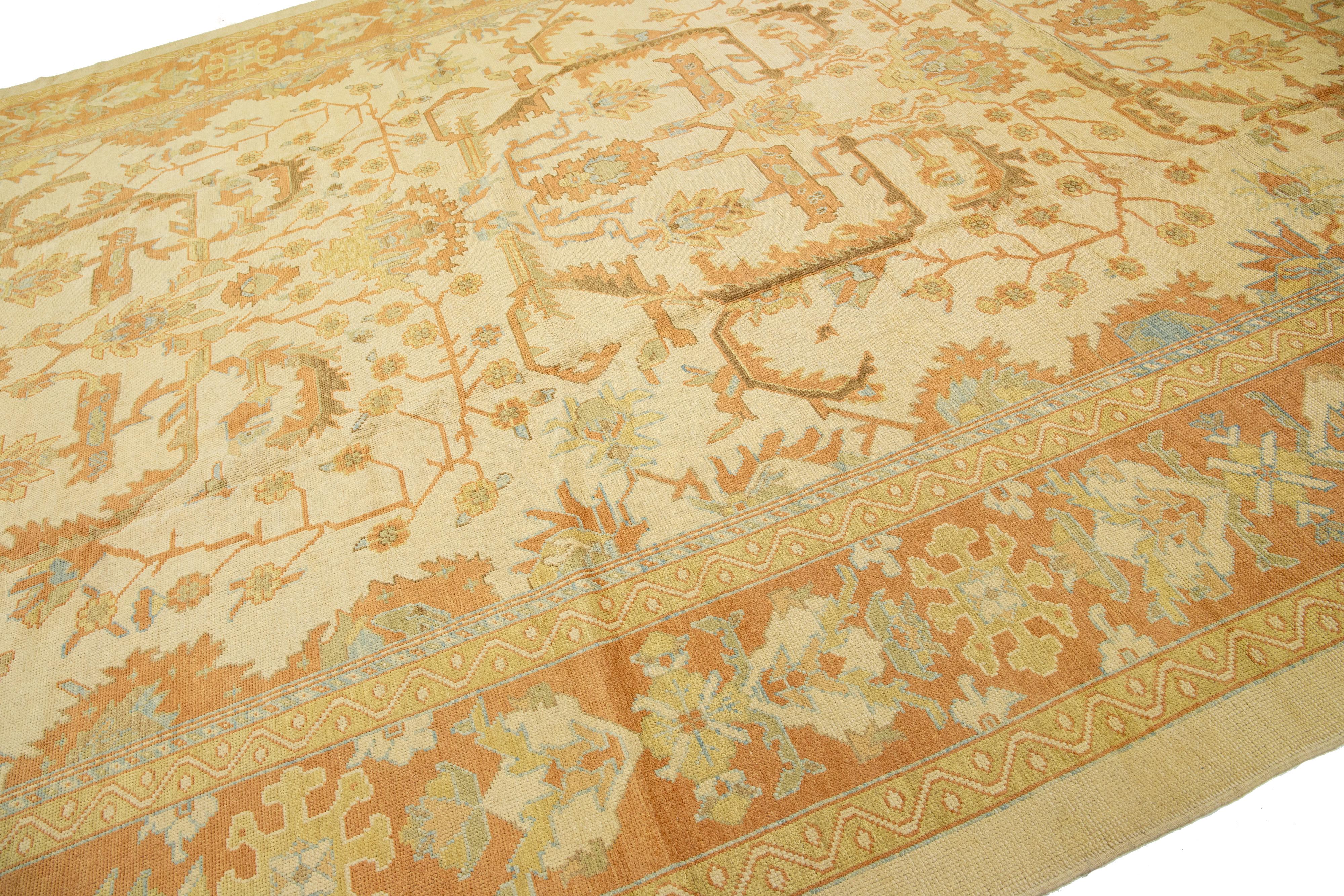 The modern Oushak rug from Turkey described here is hand-knotted. It showcases a beige background, alongside complex floral designs in peach and blue hues.

This rug measures 12'5