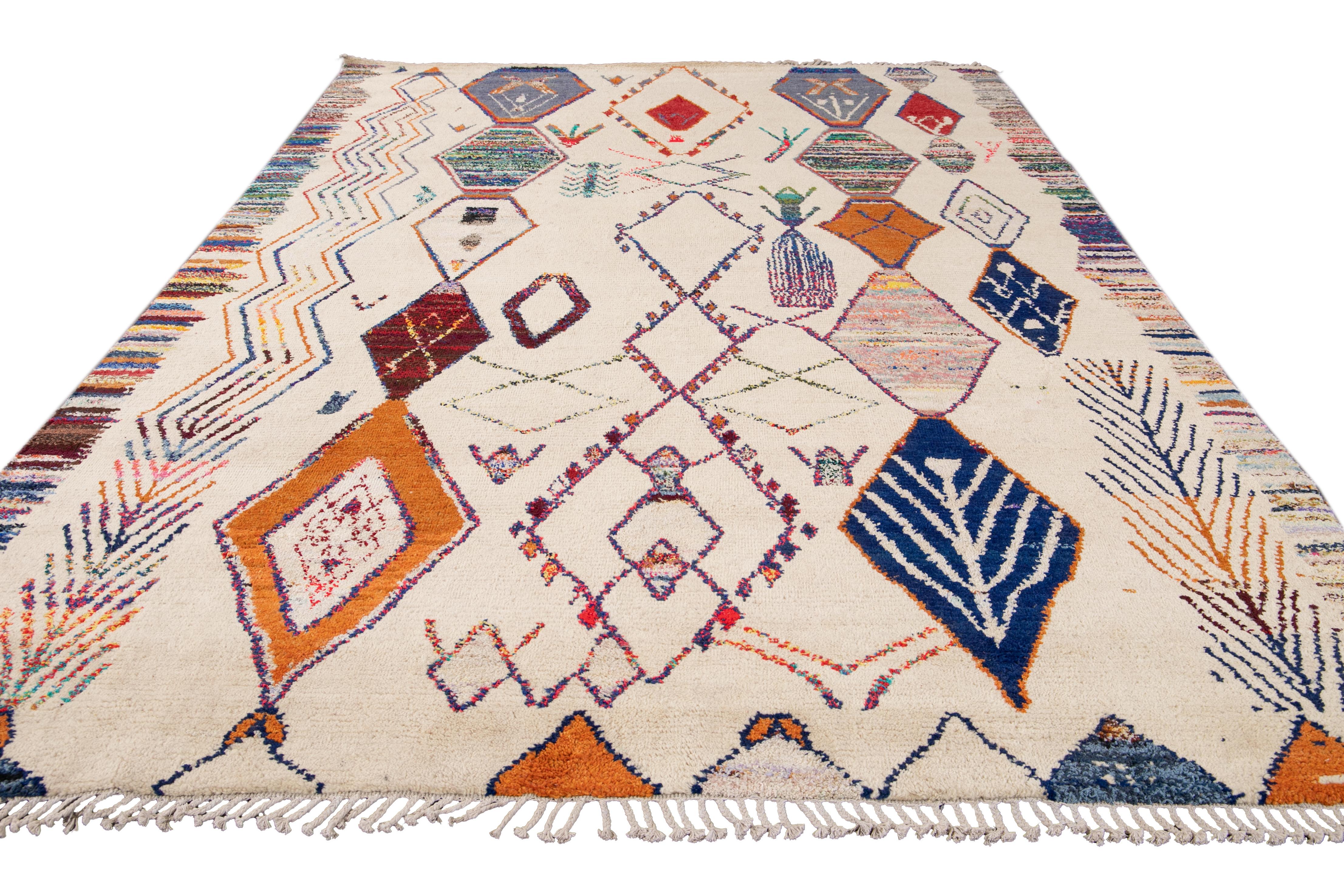 This contemporary hand-knotted wool rug showcases a stunning Moroccan-inspired style, featuring an ivory field complemented by enchanting multicolor accent hues. Its exquisite tribal pattern is accentuated by delicate fringes adorning both the top