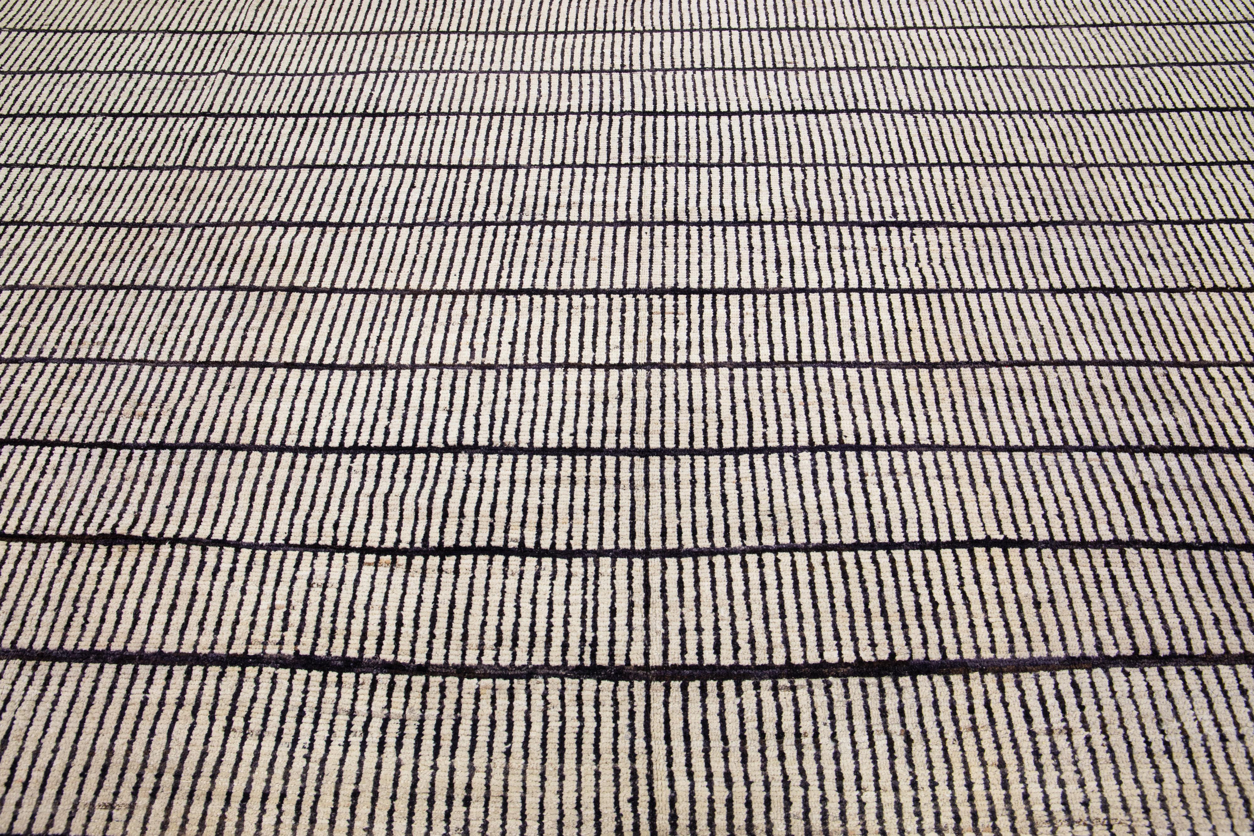 Magnifique tapis en laine nouée à la main, de style marocain, avec un champ beige. Ce tapis surdimensionné présente des accents noirs et bleus dans un motif géométrique abstrait. Il combine l'équilibre parfait entre un style traditionnel et des