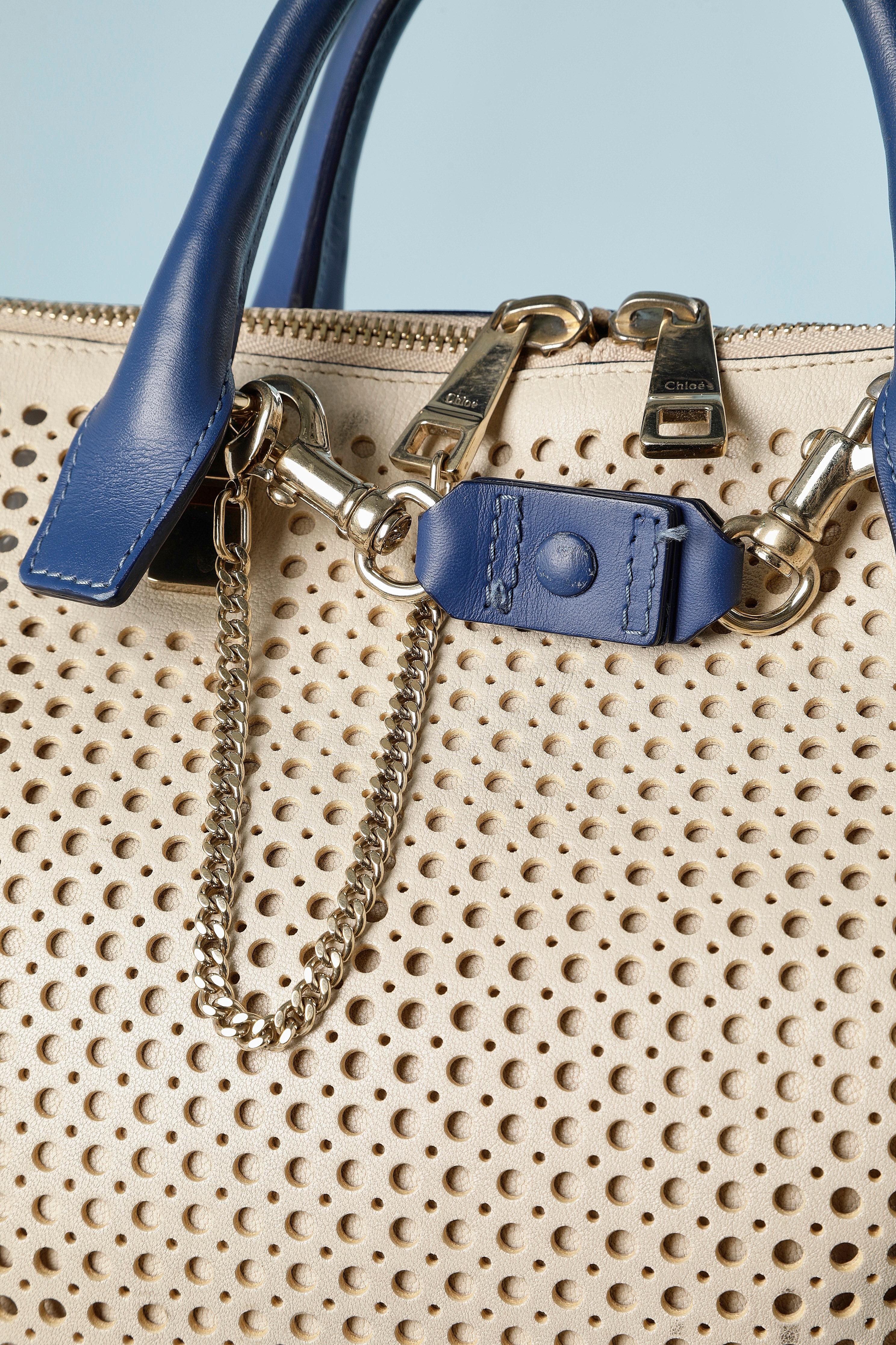 Beige perforated leather bag with blue leather handle and bottom.Zip on the top to close it and chain.  No lining. Shoulder strap is missing. Authenticity card provided. 2 inside pocket with zip.
SIZE 40cm X 25cm X 15 cm 