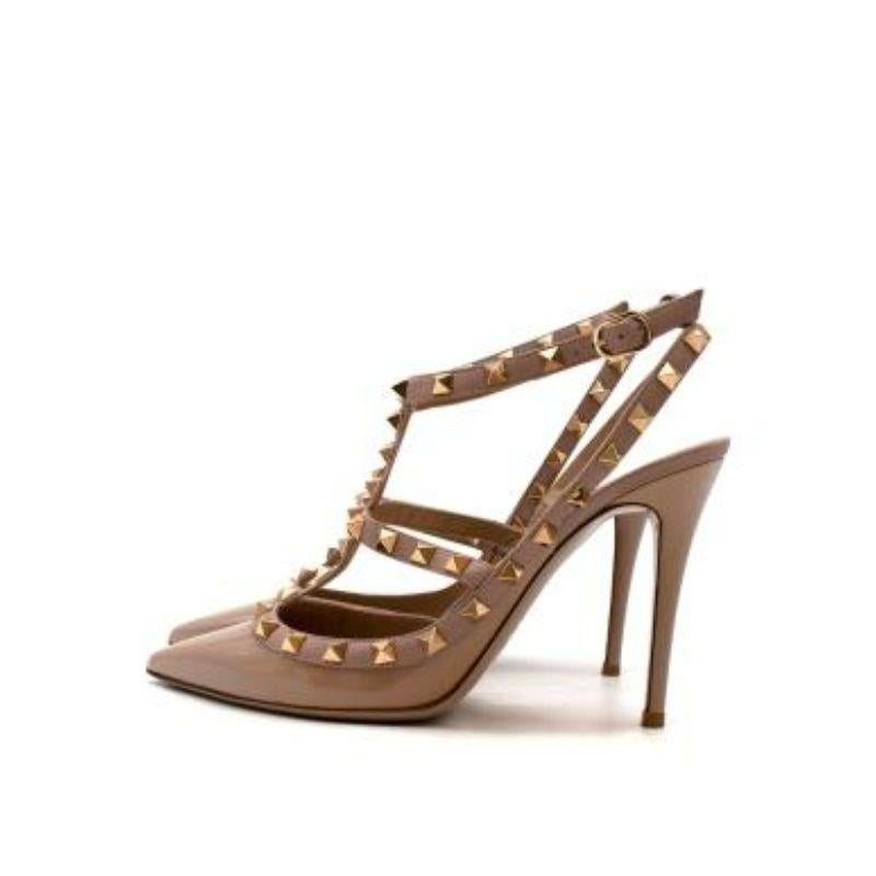 Valentino Beige Rockstud Patent Leather pumps
 
 - Nude patent leather pointed toe pumps set on a 10.5cm stiletto heel 
 - Platinum-plated pyramid studs along the t-bar straps 
 - Buckle fastened ankle strap 
 - Beige leather interior with branded